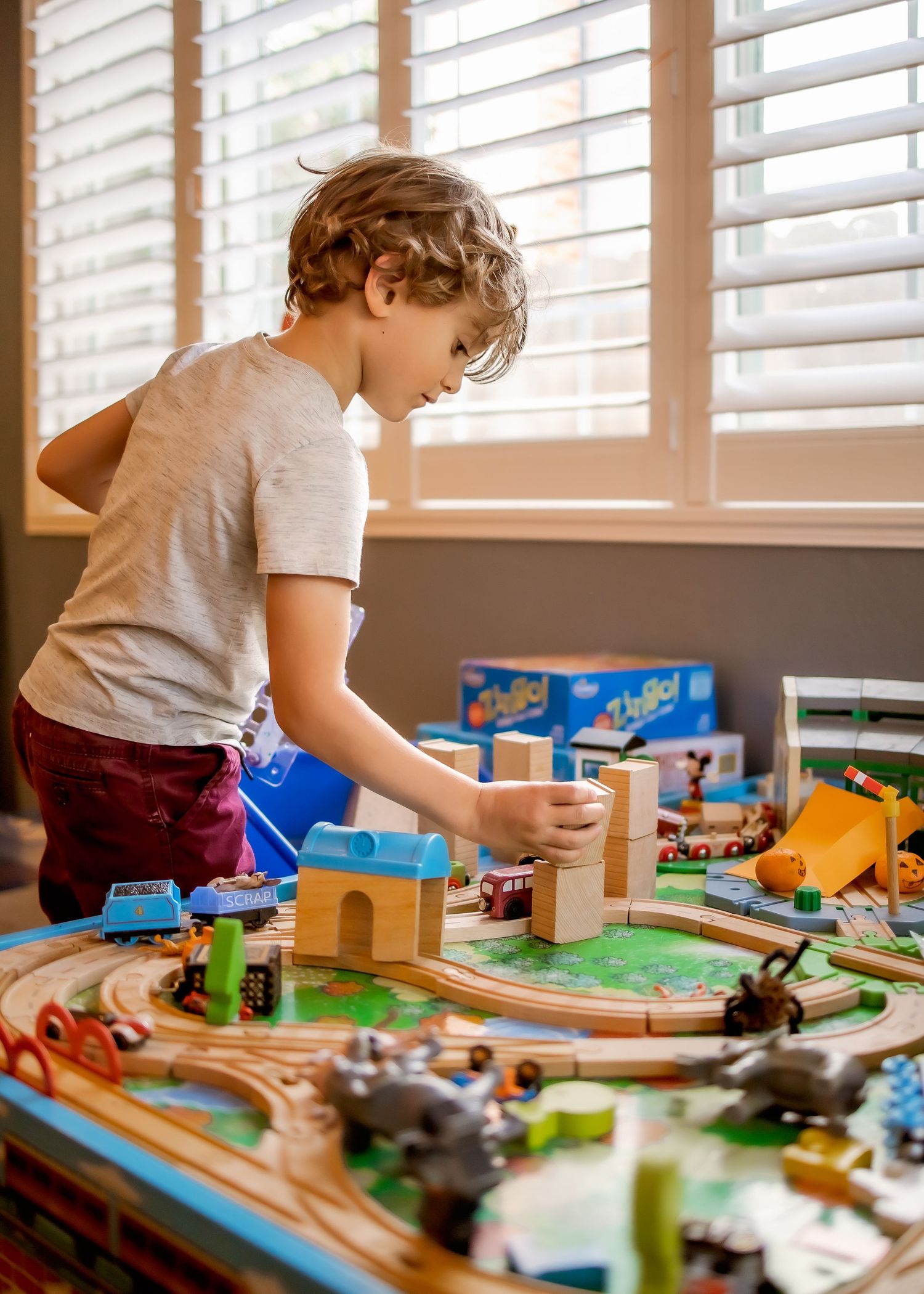 close-up of a train table with a boy arranging blocks on it