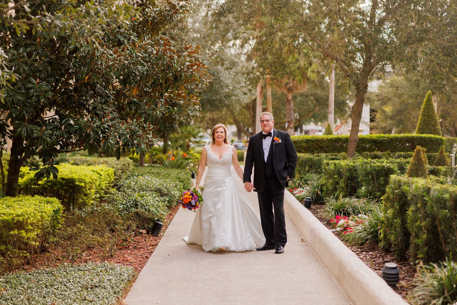 A couple walking together on a garden path during their wedding day at an elegant venue.