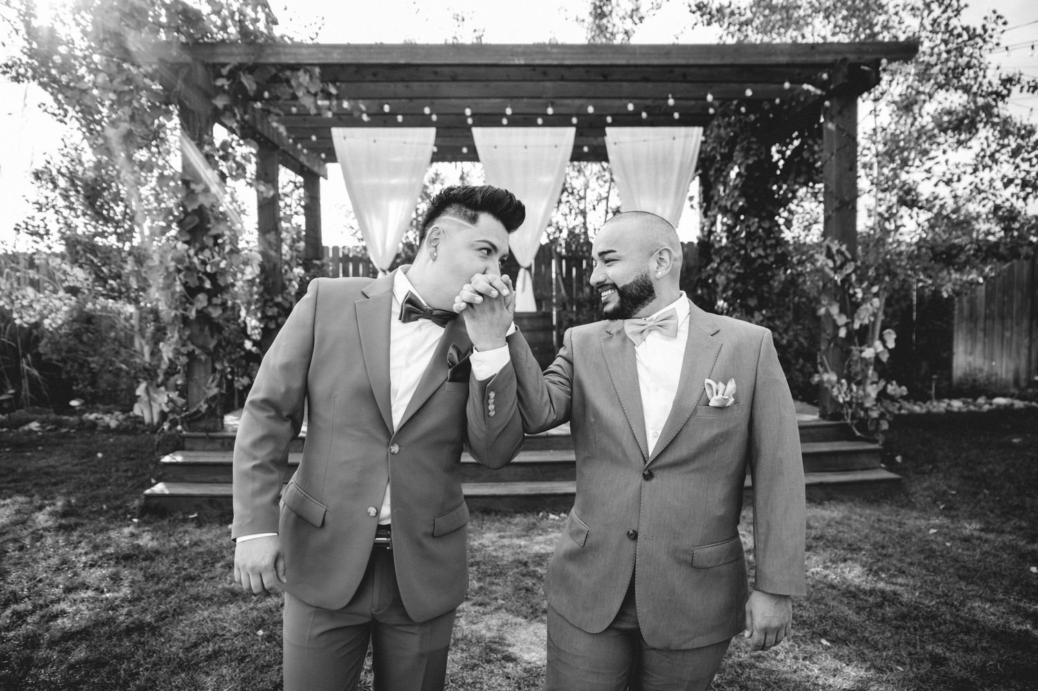 Black and white photograph of emotional moment between two people under a garden pergola.