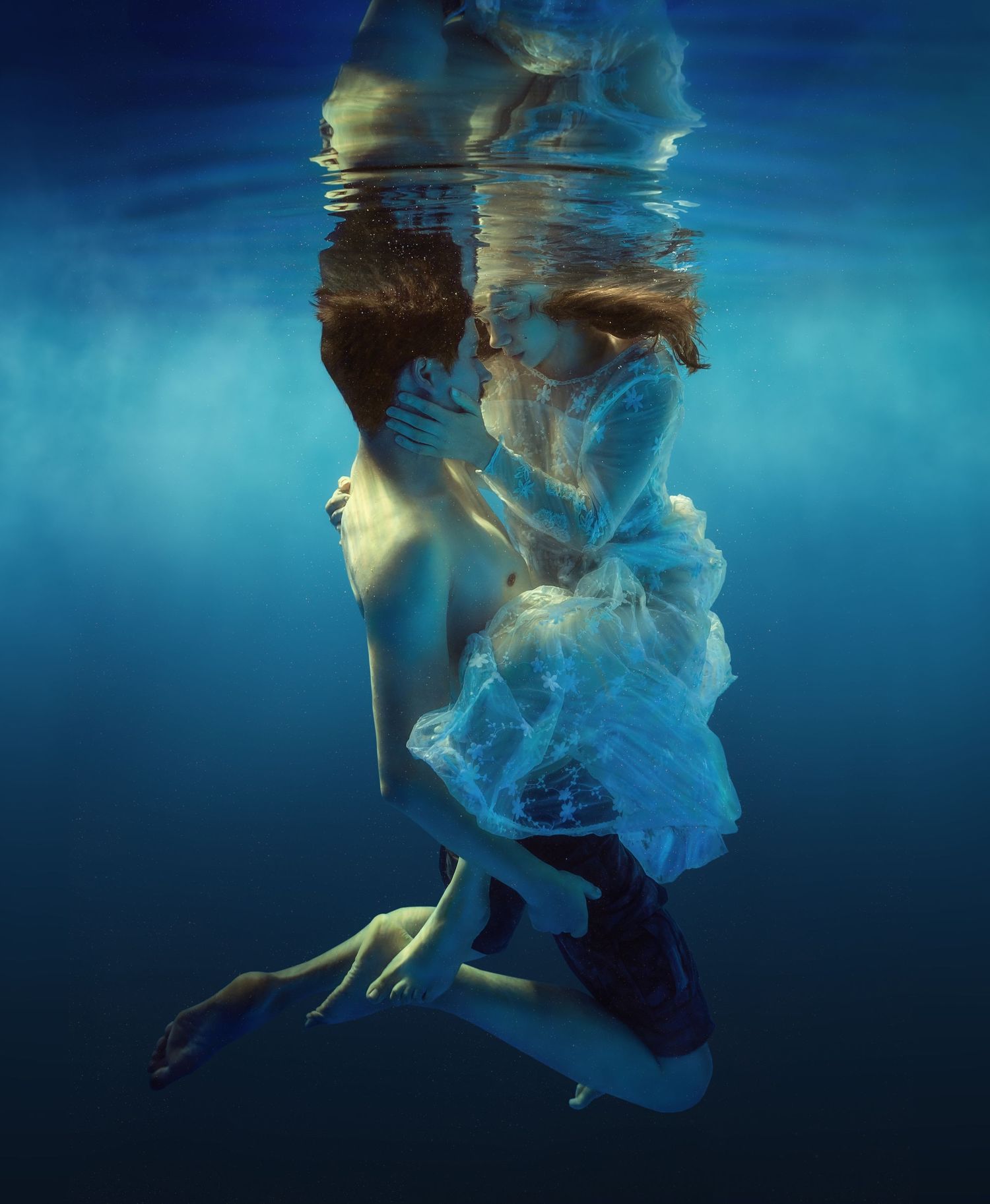 Couple kissing beneath clear blue water