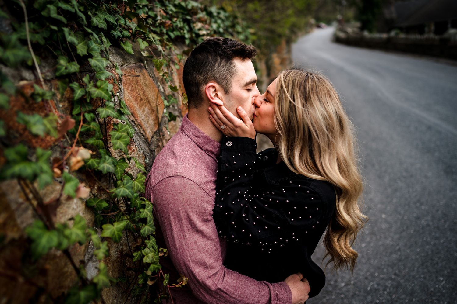 Romantic autumn engagement photo shoot with couple embracing on a leaf-covered path.