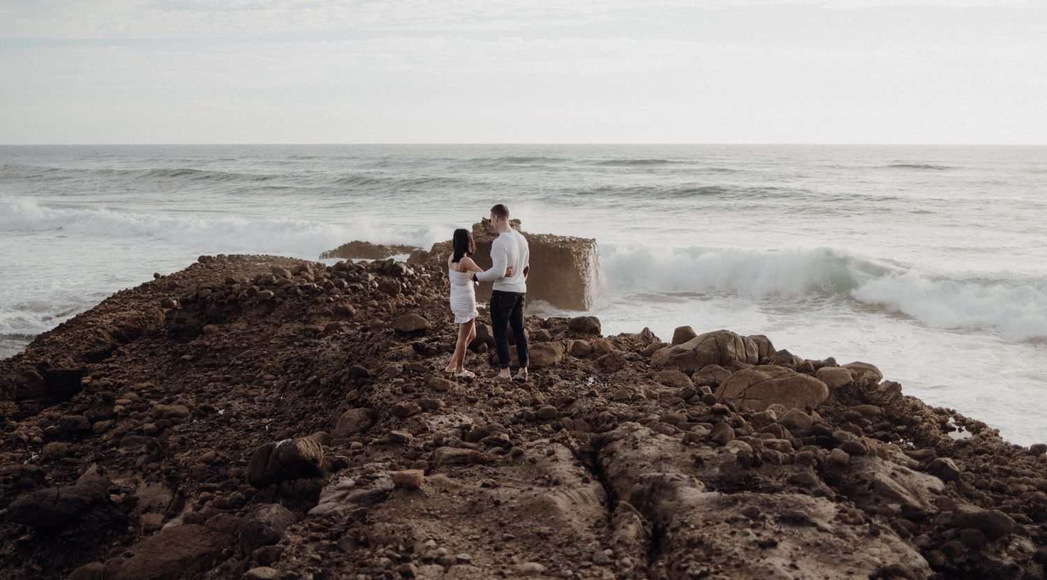A couple standing near the cliff in their post-wedding shoot with Apertured Media-Auckland Wedding Photographer