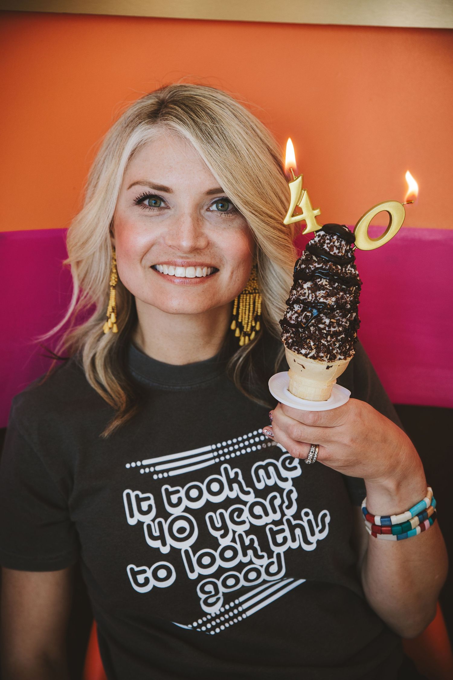 Birthday celebration with ice cream cone and candles against colorful background.