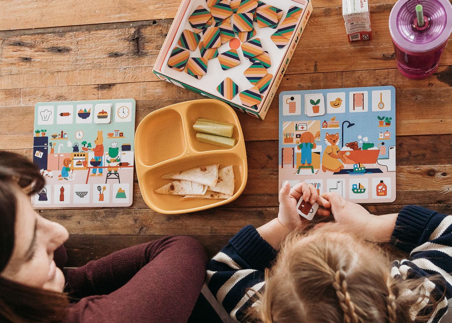 Overhead view of family playing with educational toys on wooden table.