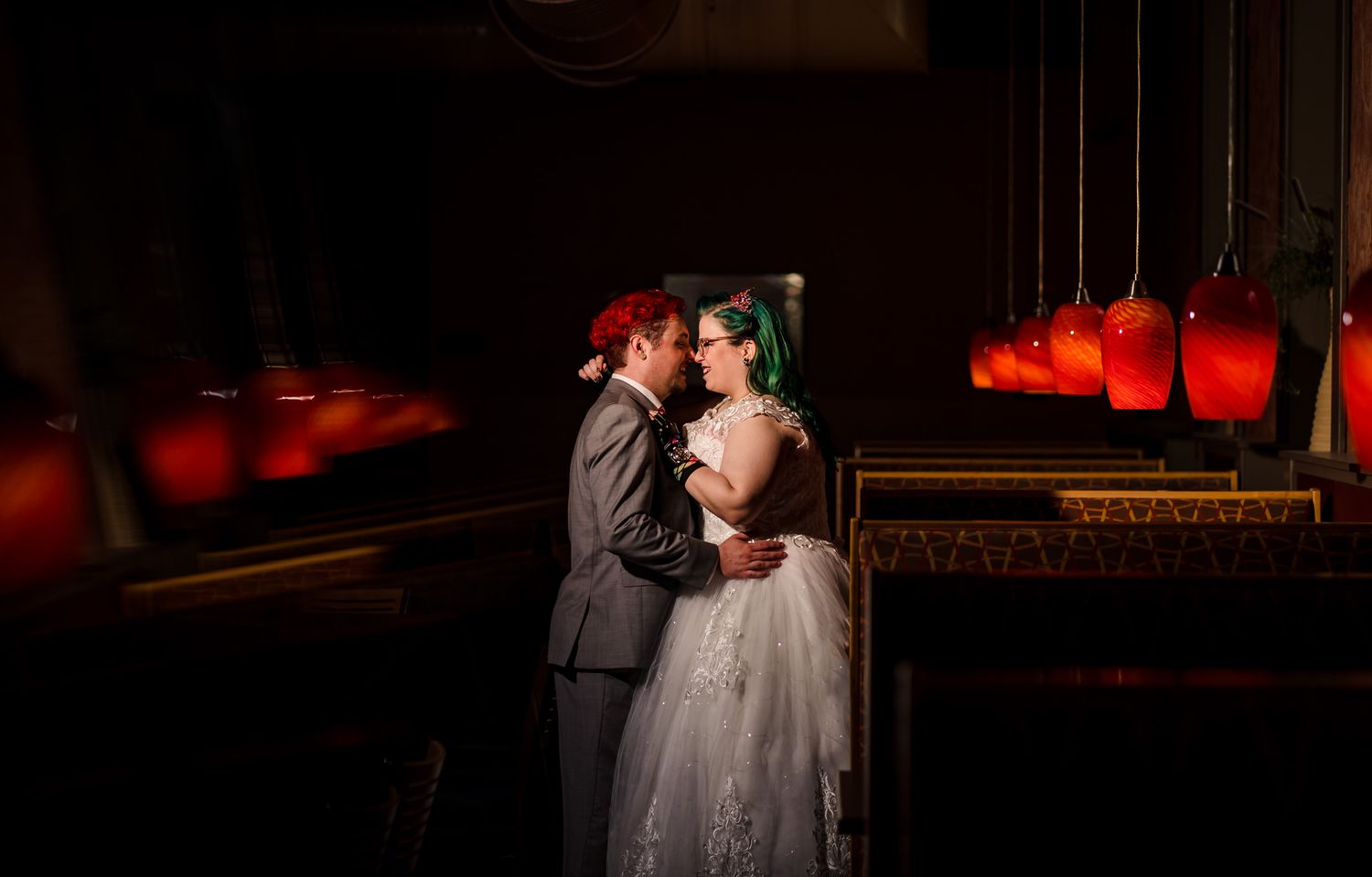 Wedding celebration at night with red lighting and string lights creating a dramatic atmosphere.