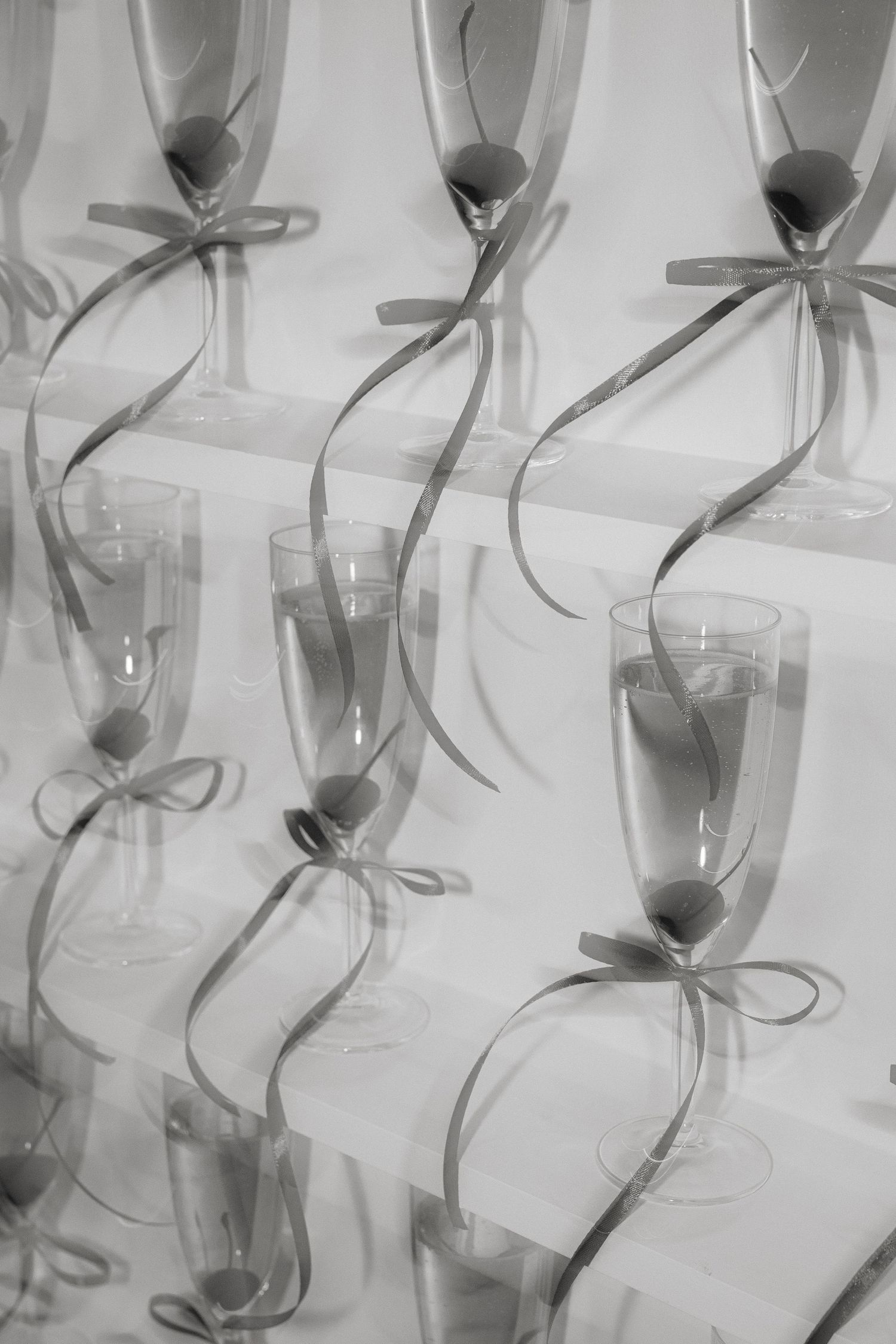 Row of champagne glasses decorated with grey ribbons in minimalist black and white style.