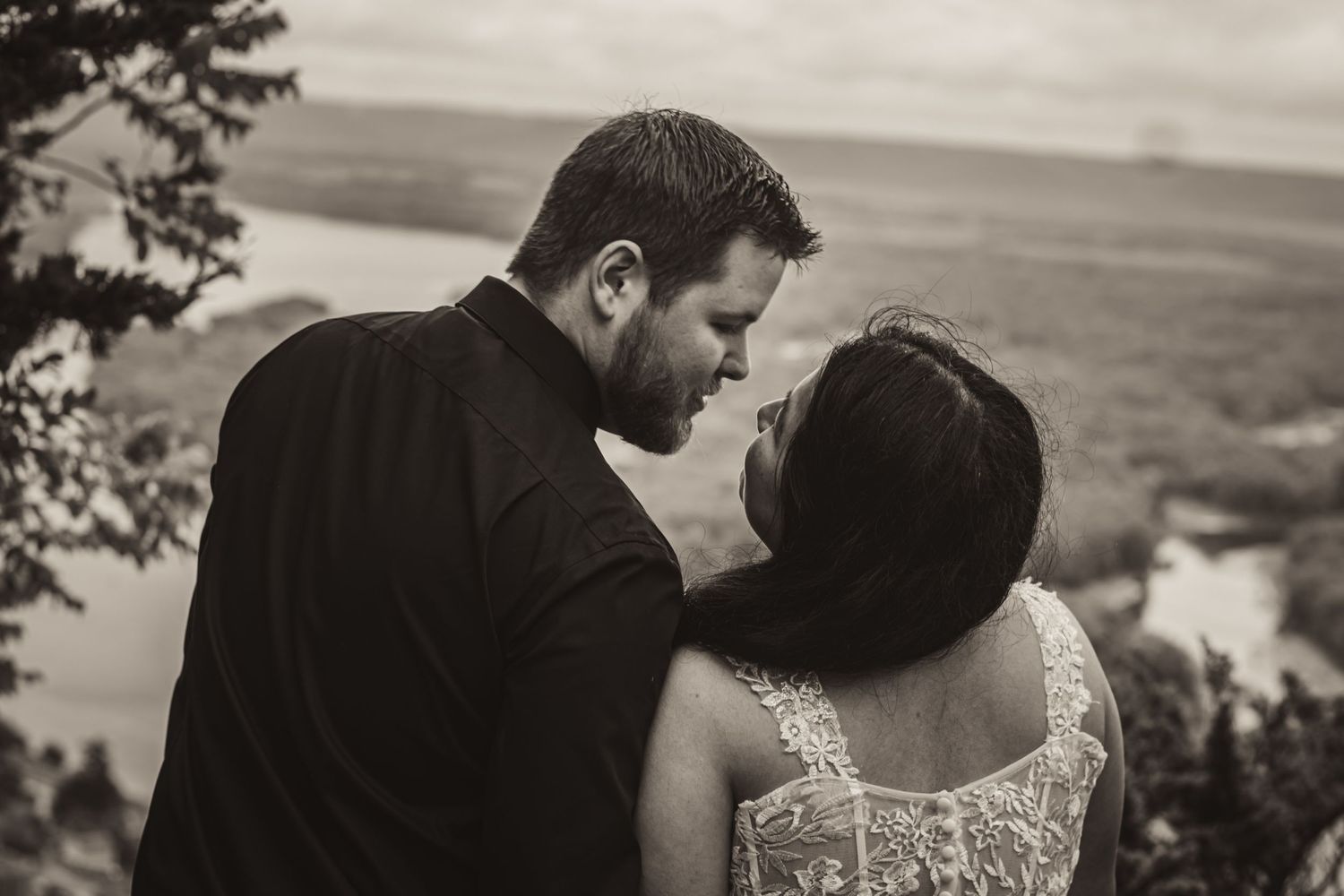 Intimate moment captured between couple overlooking scenic mountain landscape.
