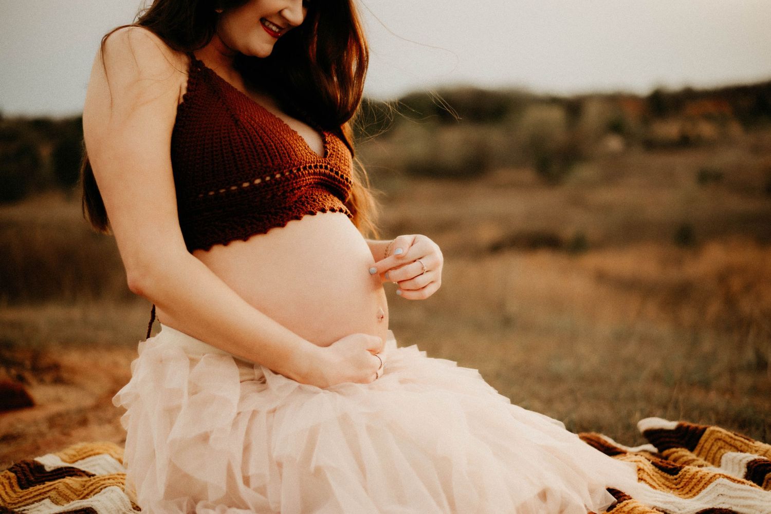 Intimate maternity session on a picnic blanket at golden hour.