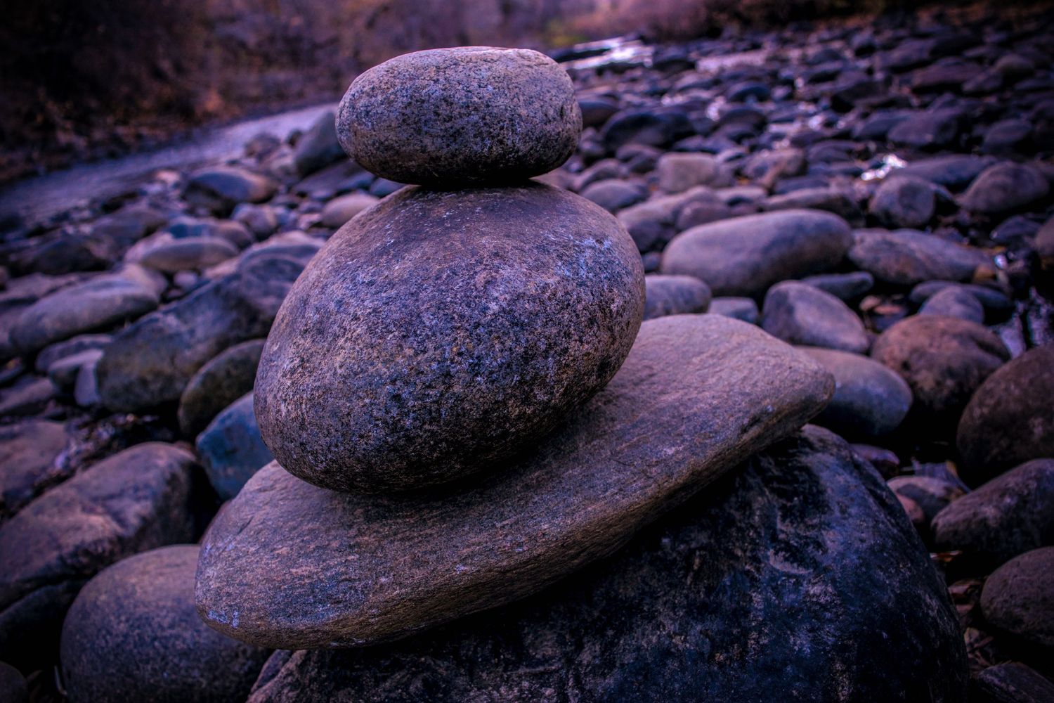 Smooth river rocks balanced in a zen-like stack at twilight.