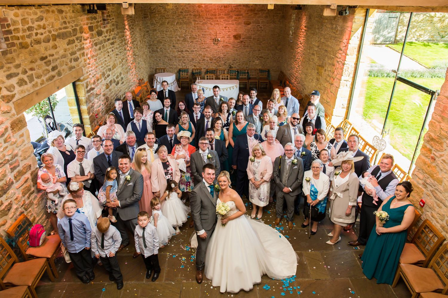 Overhead view of wedding party and guests gathered in rustic brick venue space.