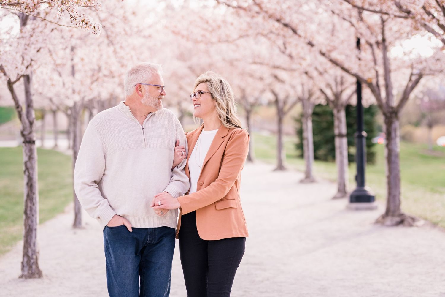 Engaged couple walking arm in arm through the cherry blossoms at the Utah State Capitol Building