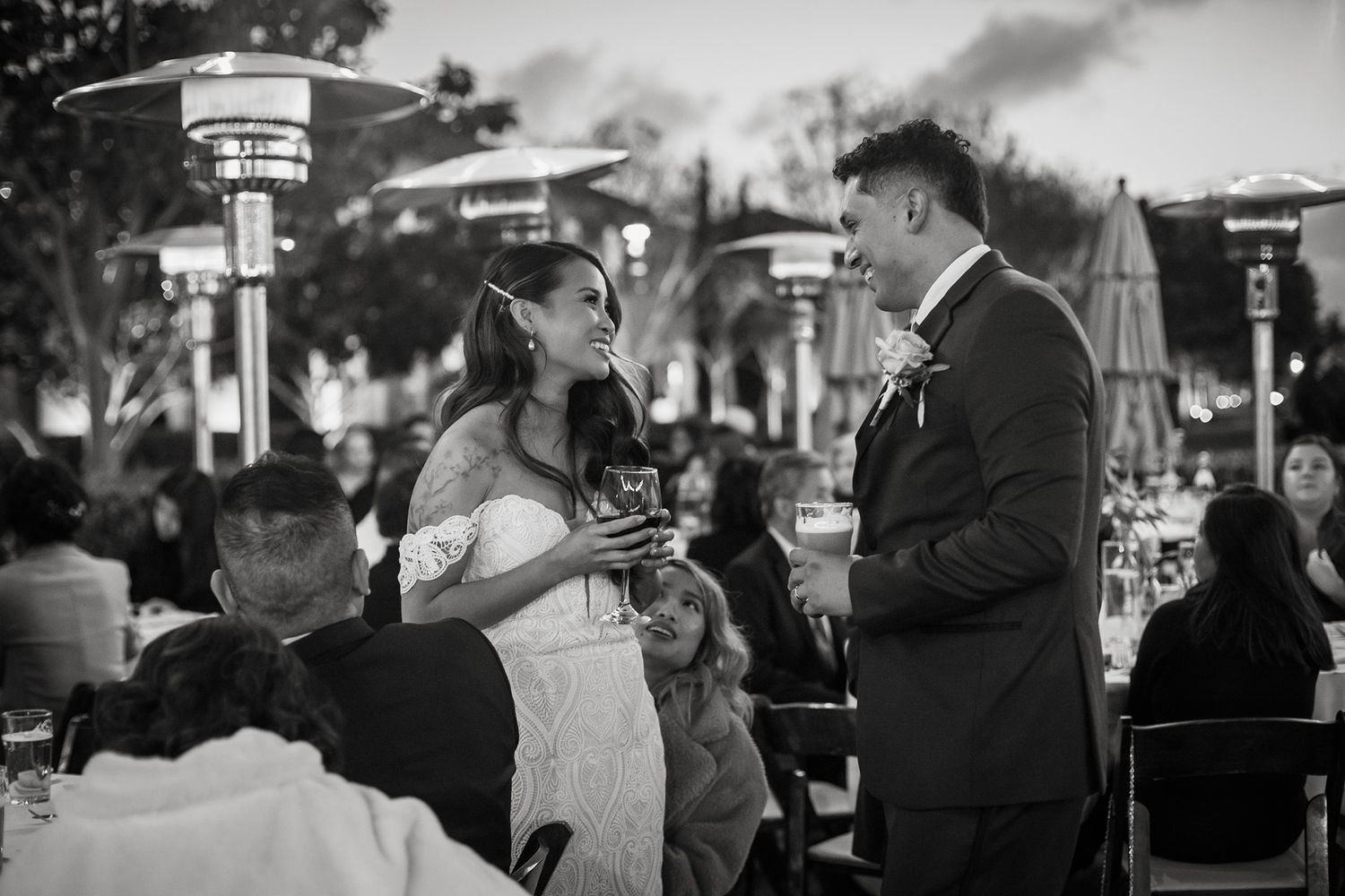 Black and white photo of a bride and groom mingling at an evening reception at Stone Brewing Liberty Station in San Diego.
