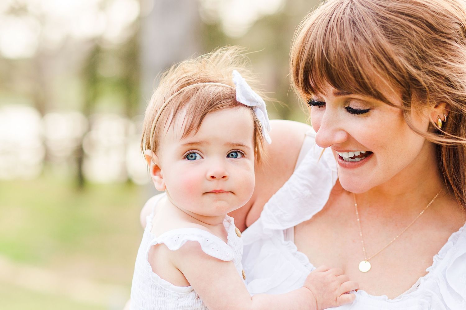 A tender moment between parent and baby outdoors in soft natural lighting.
