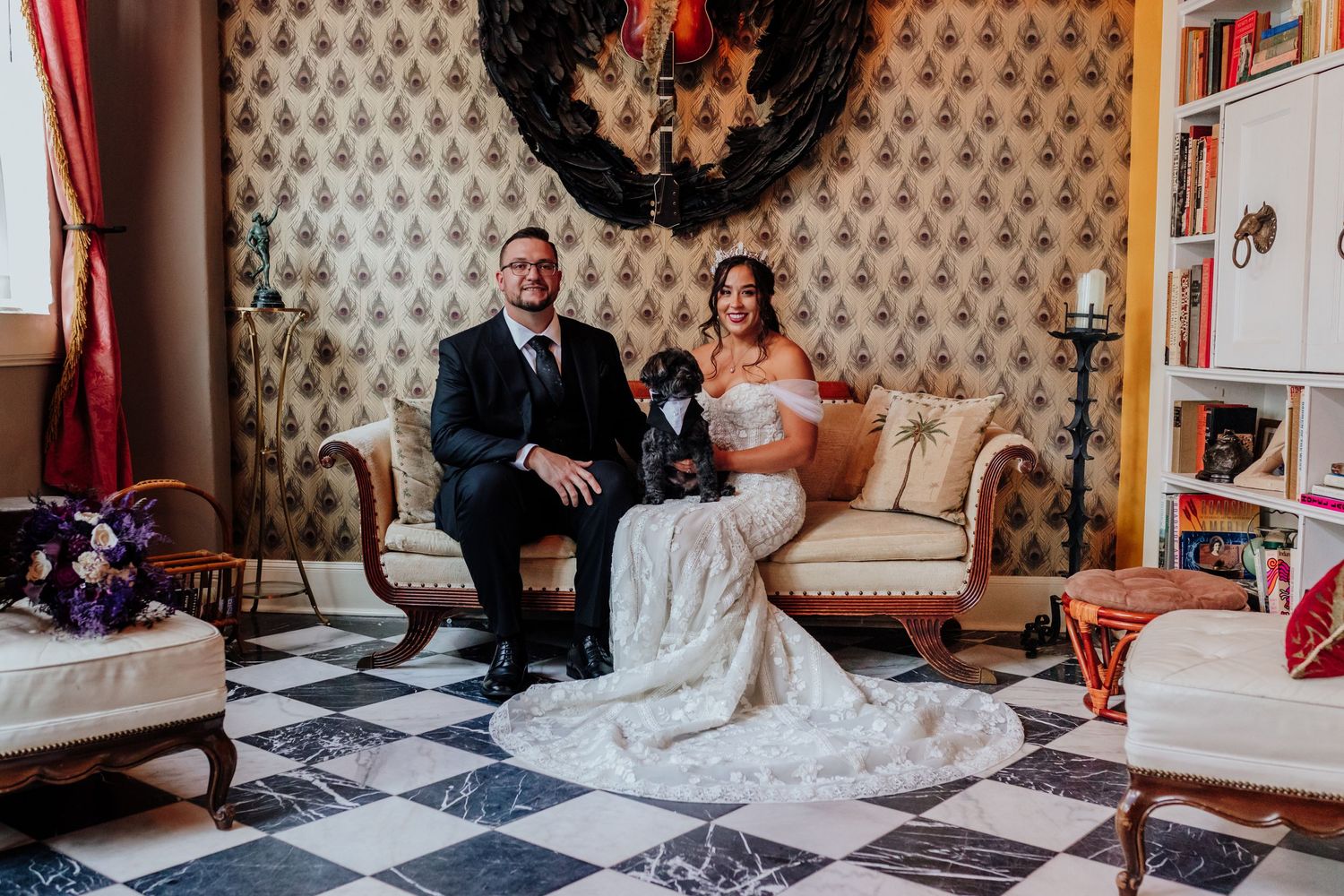 Elegant wedding couple seated on vintage tufted sofa in a room with checkered floor.