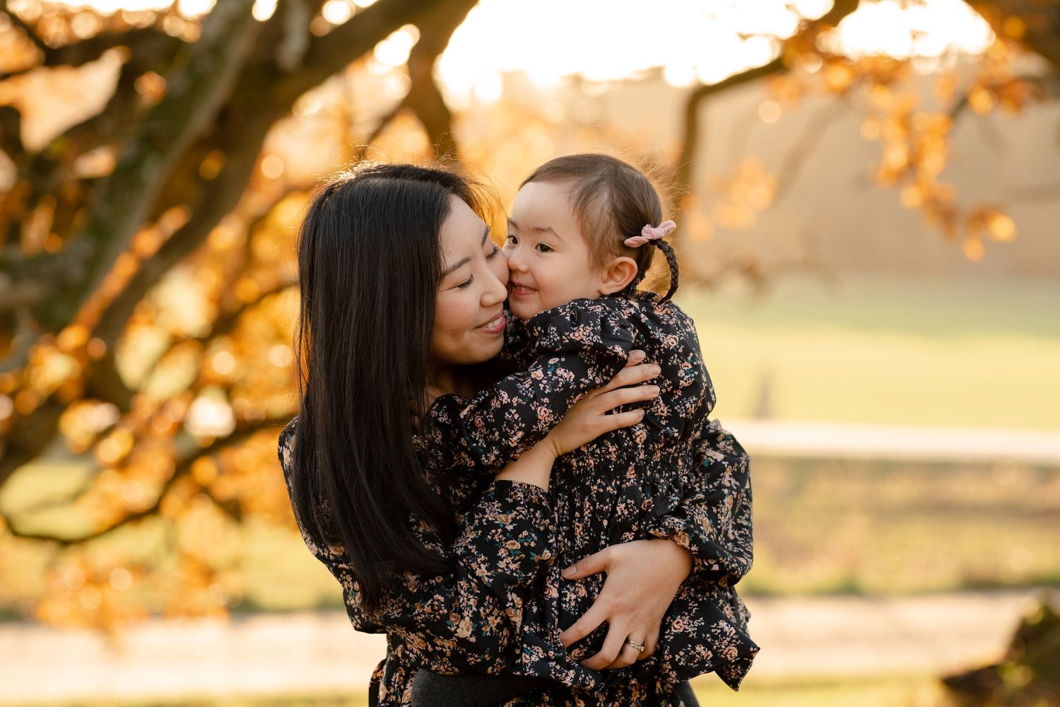 Tender moment captured between parent and child during golden hour beneath autumn trees.