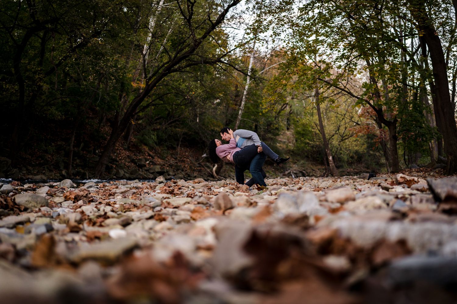 Autumn forest path covered in fallen leaves during golden hour sunset.