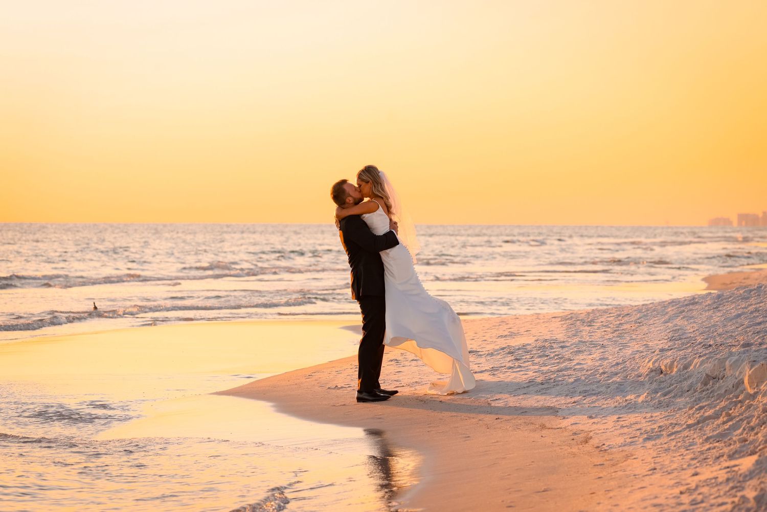 A romantic silhouette of a couple embracing on a beach at sunset with waves in the background.