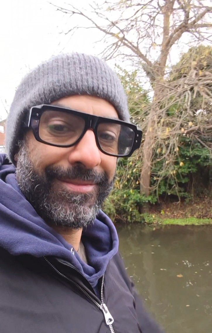 A series of selfies taken outdoors near a pond showing someone wearing glasses, a grey beanie and navy hoodie.