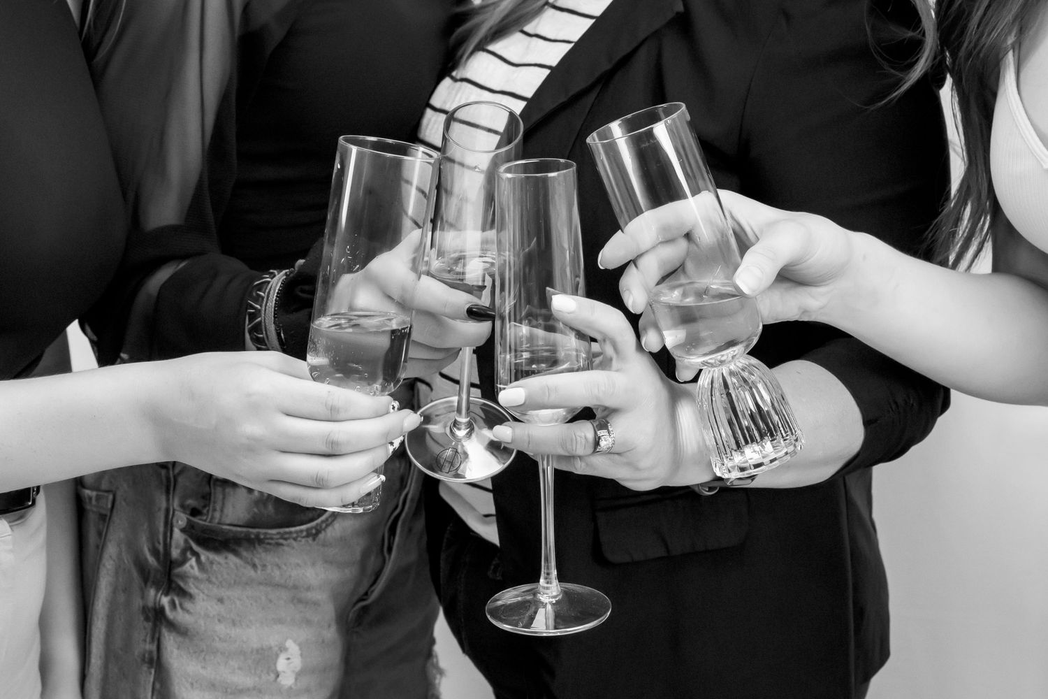 close up black and white photo of glasses clinking held by 4 women