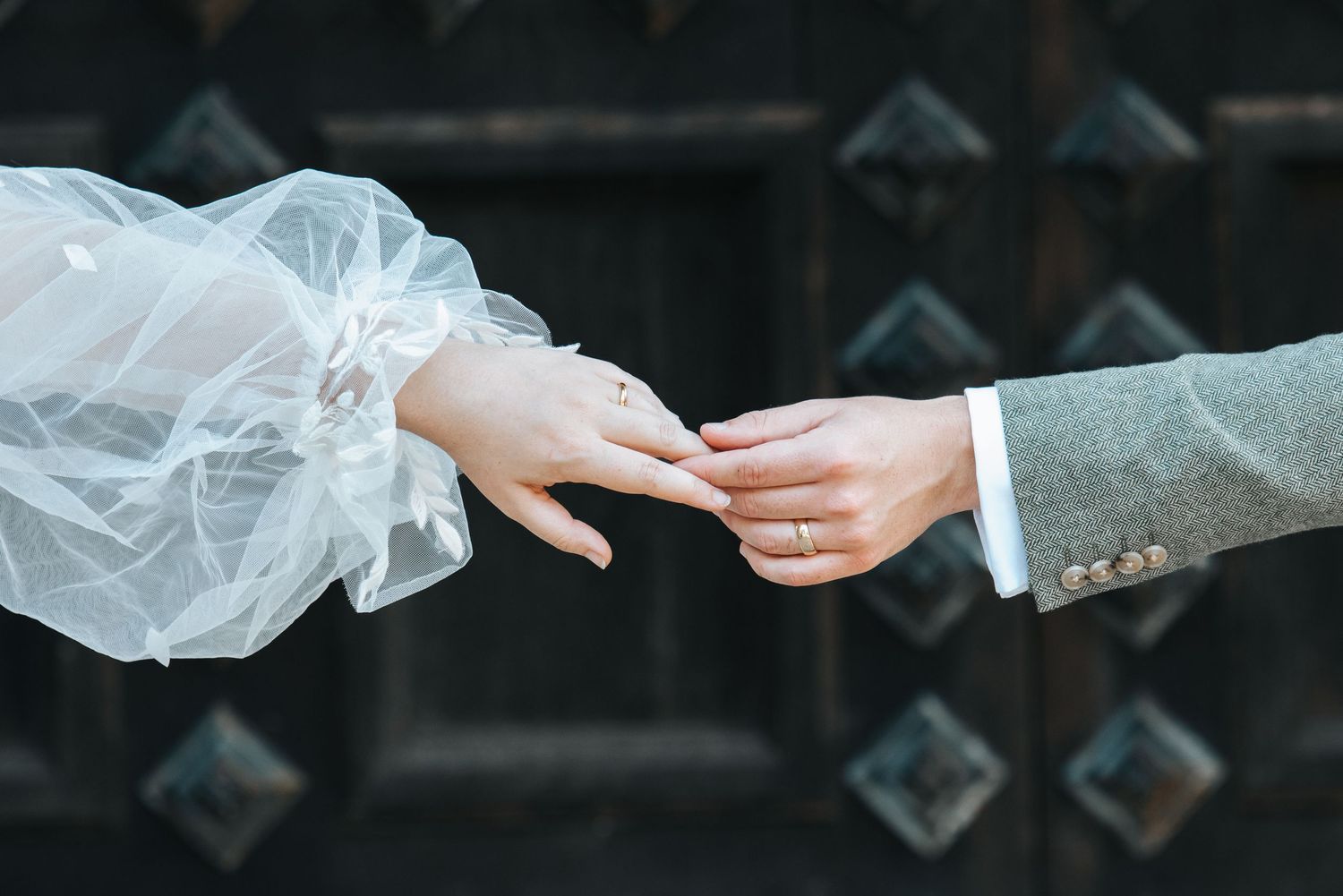 Close-up detail of hands exchanging rings during a wedding ceremony.