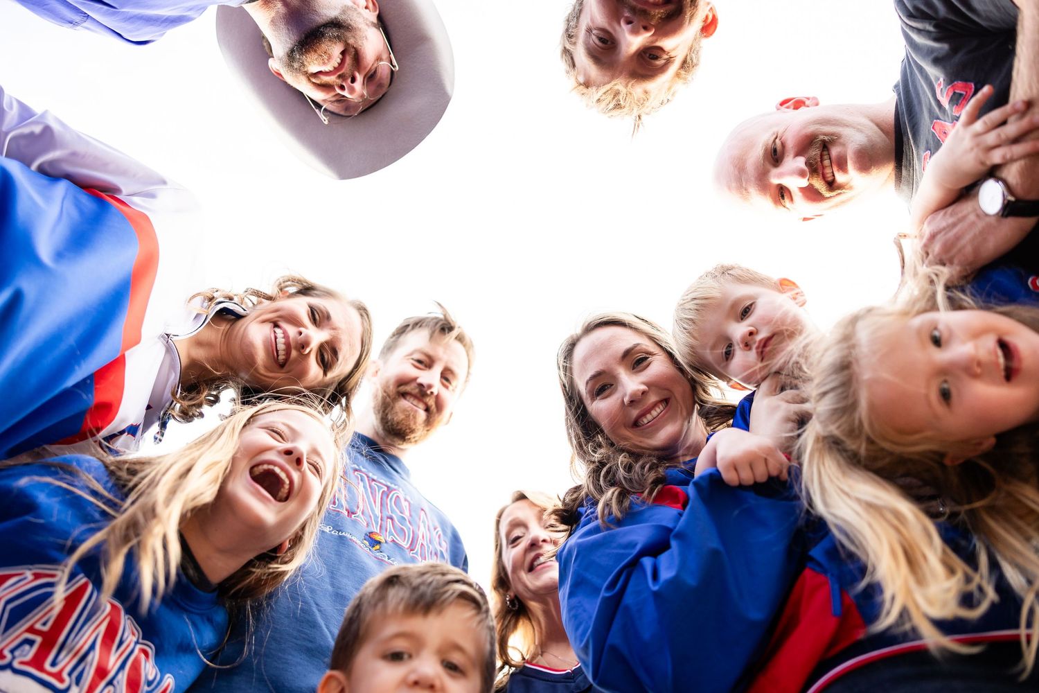 A group of sports fans cheering and celebrating together while wearing blue and red team colors at an outdoor event.