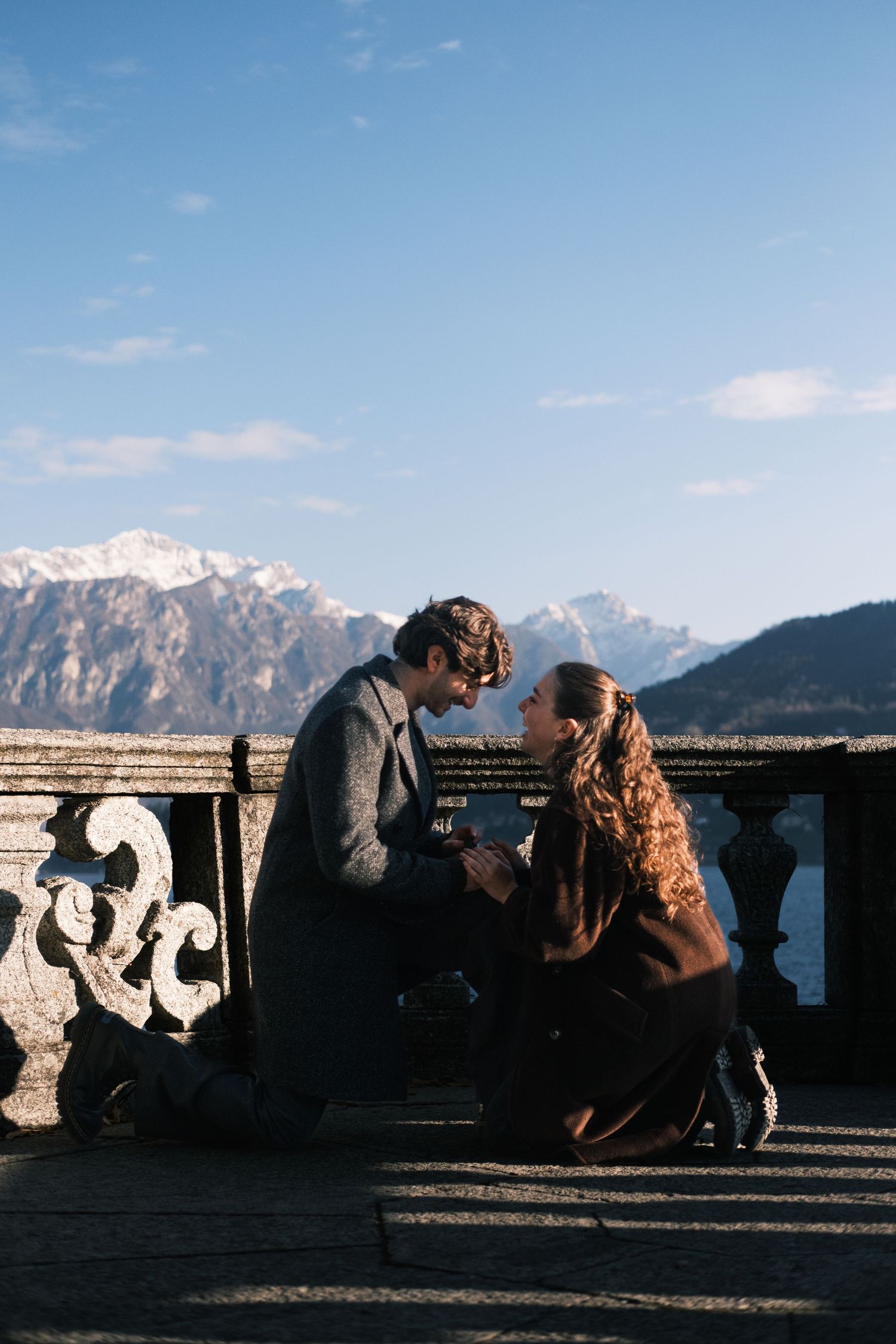 Silhouettes of people photographing mountain views from an observation deck at sunset.