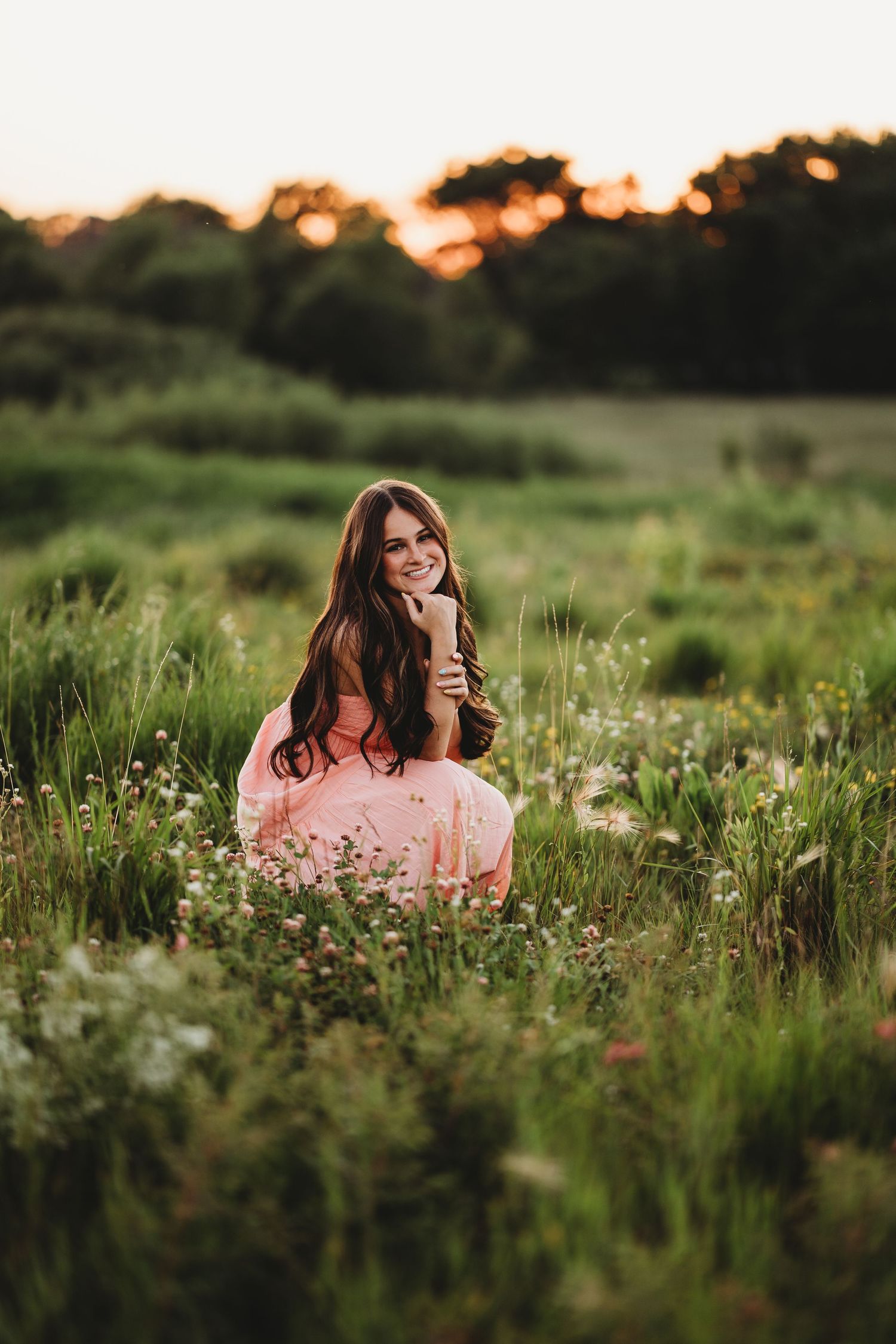 Sunset portrait session in a wildflower meadow with soft pink tones.