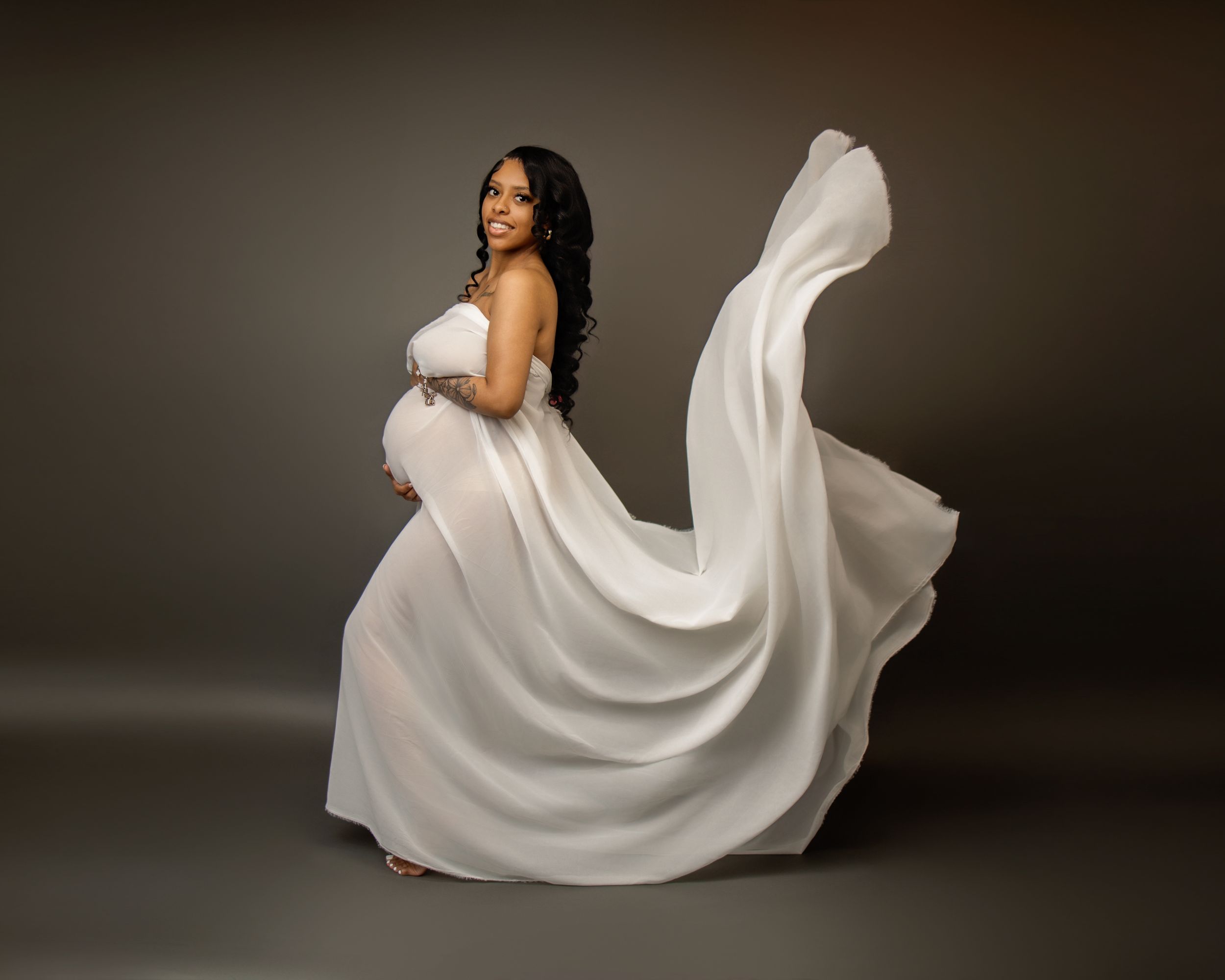 Fluid motion captured in white flowing fabric against dark background creates dramatic twirling dance effect in portrait series.