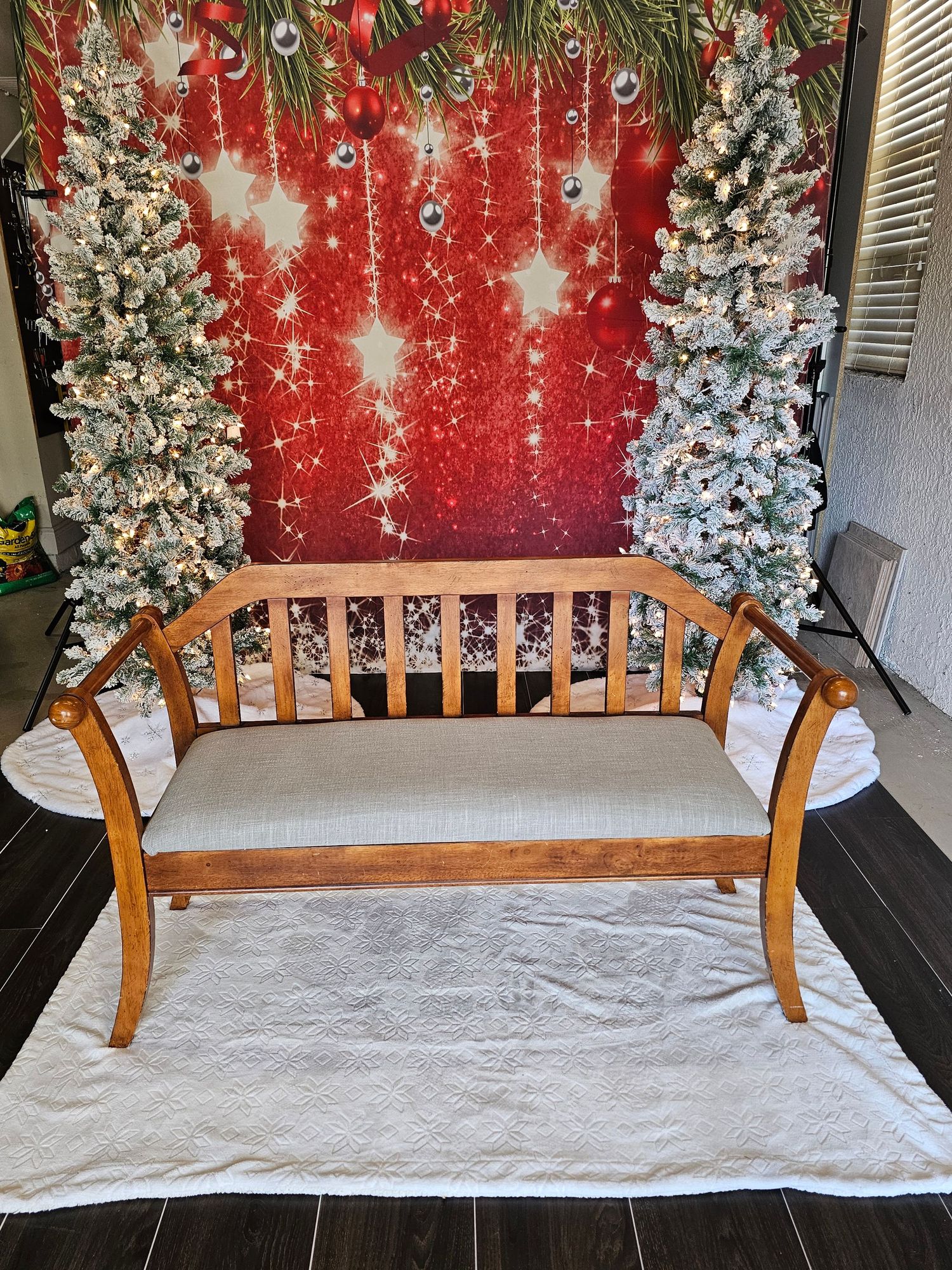 A festive holiday photo backdrop with white flocked Christmas trees, red wall, and white floor covering.