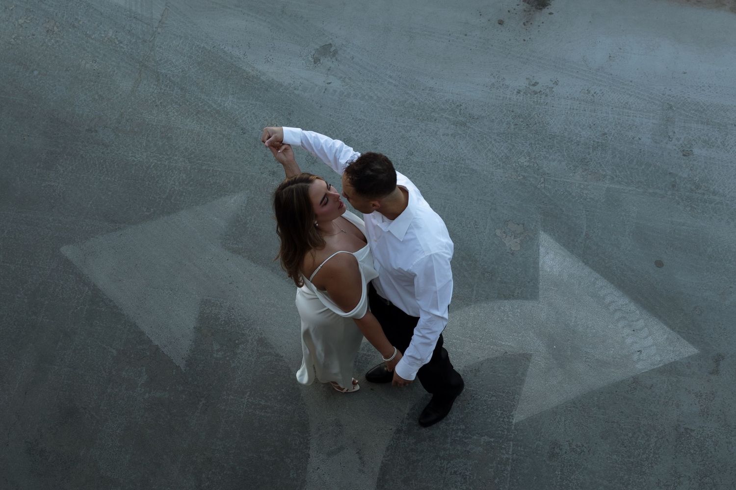 A couple dancing together on a concrete floor with directional arrows painted beneath them.