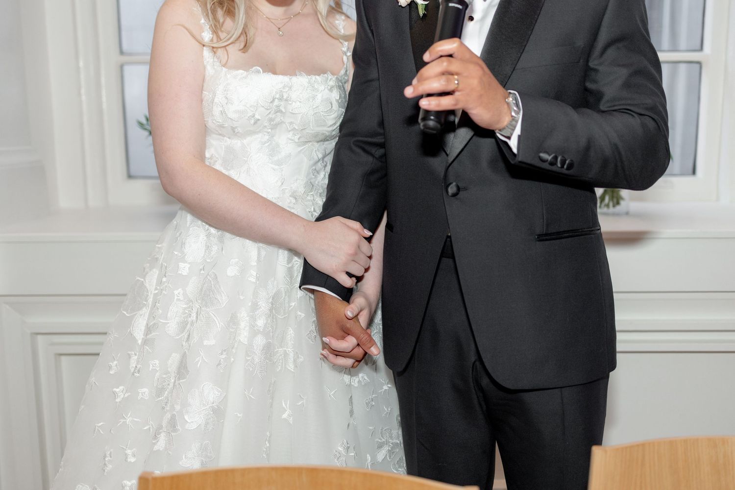 Close-up detail of delicate white lace wedding dress with pearl button closures along the neckline.
