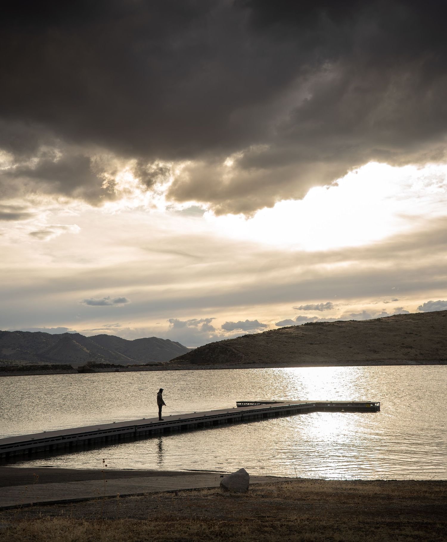 A fisherman fishing in a lake at sunset in Utah.