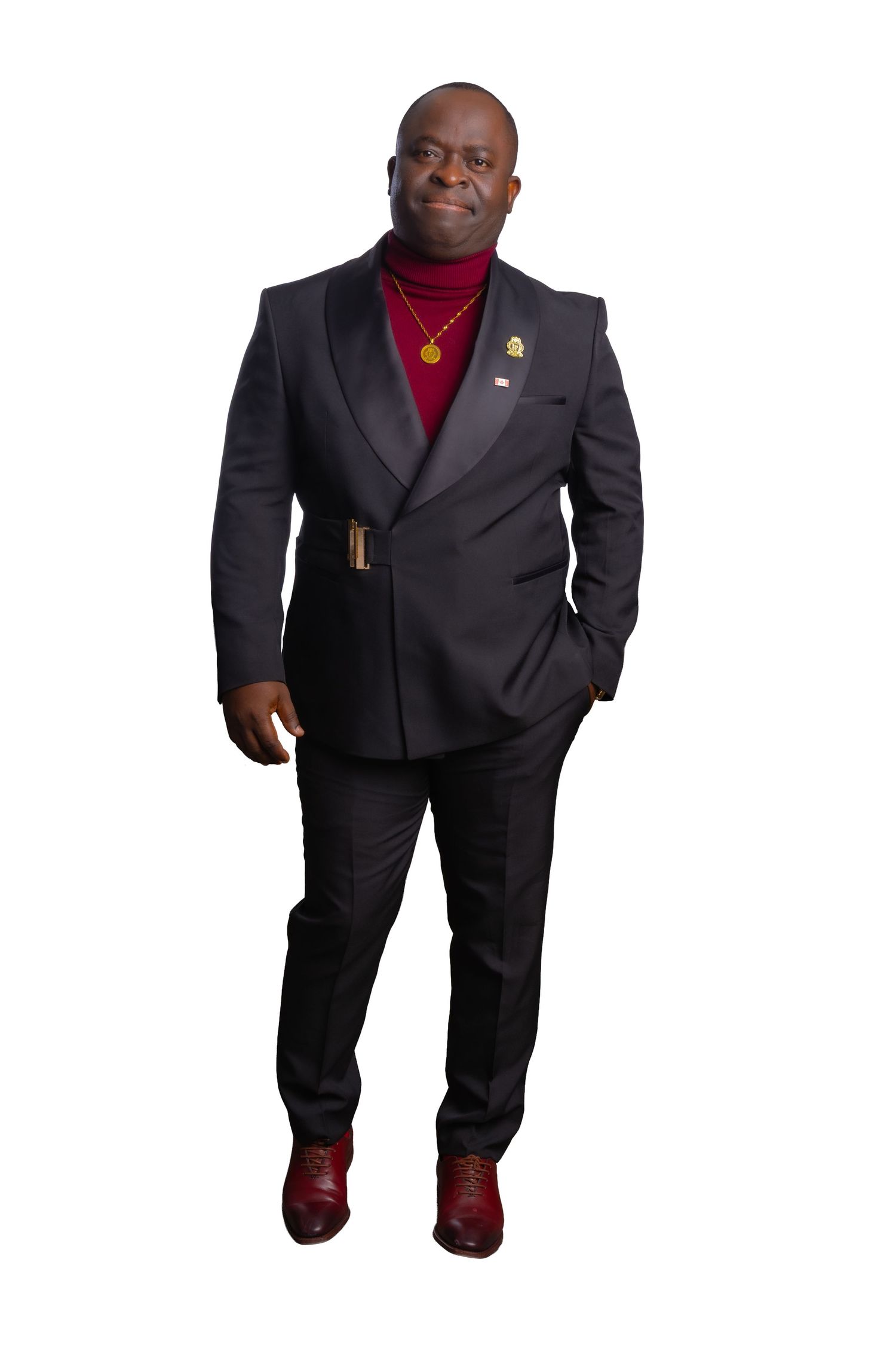 Professional portrait of someone in a black suit and red turtleneck smiling warmly against a light background.