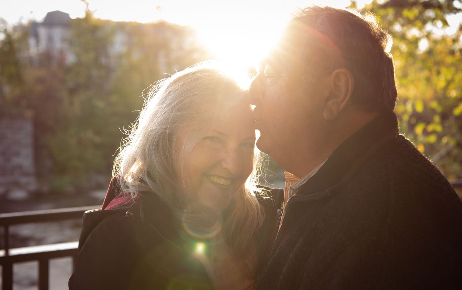 An elderly couple shares tender moments in four connected photos against a stone wall background.