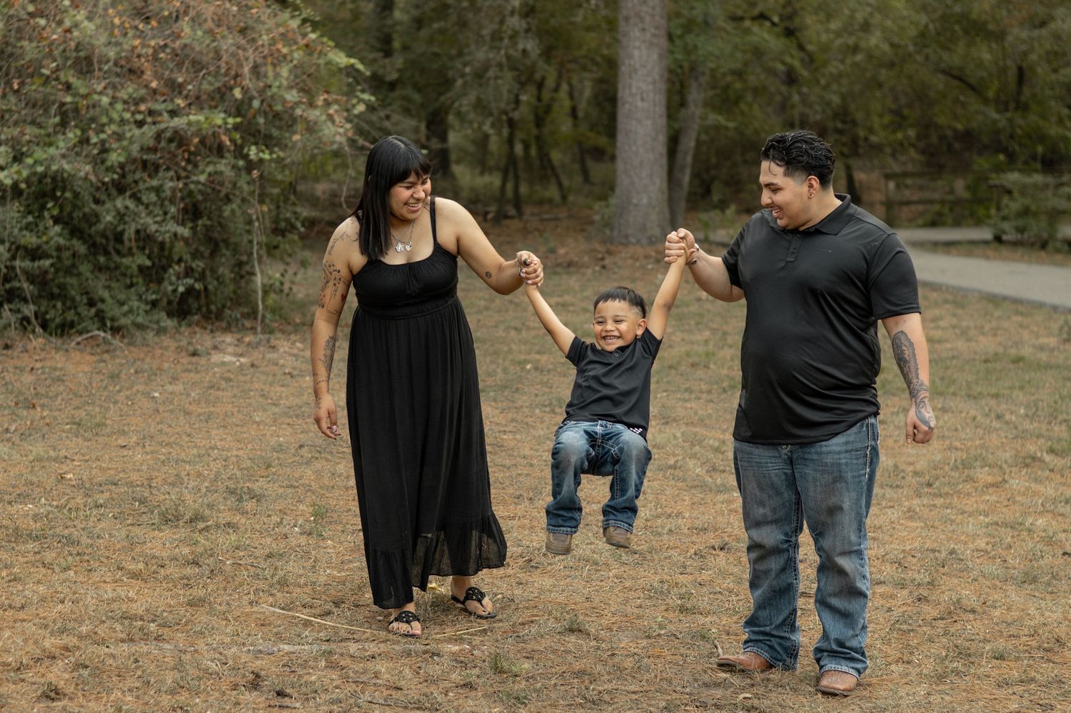 A family plays together in a grassy outdoor area during a casual photo session.
