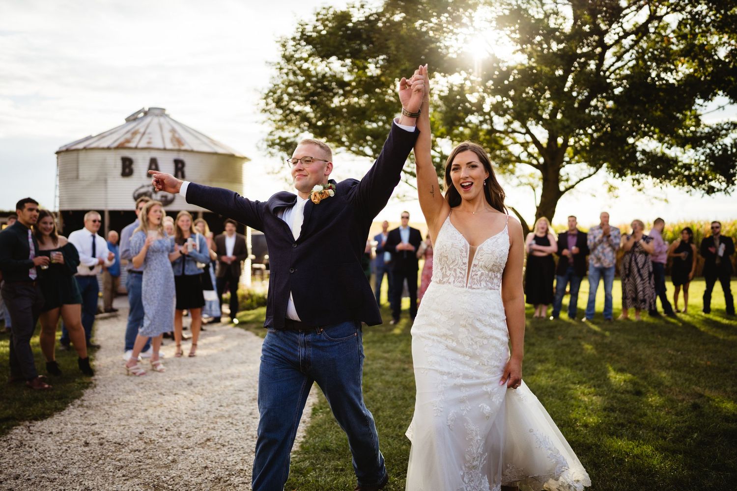 Wedding celebration guests dancing and having fun outdoors during golden hour at a rustic countryside venue.