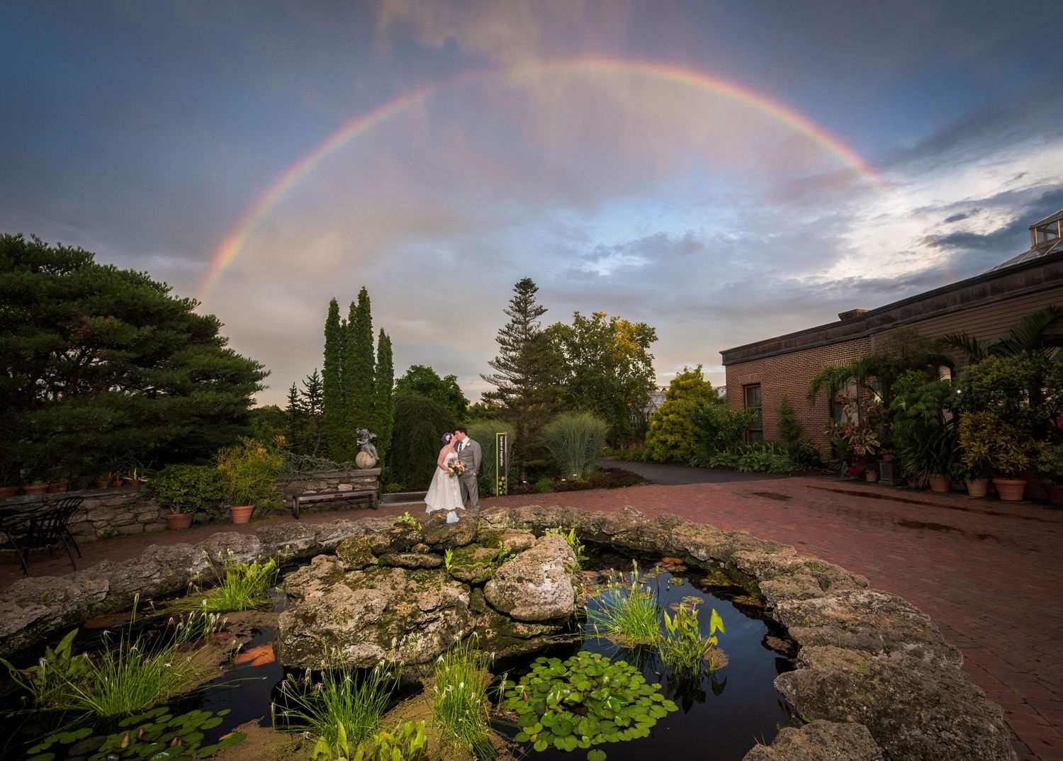 Romantic wedding couple poses in a spring garden with hanging white decorative spheres.