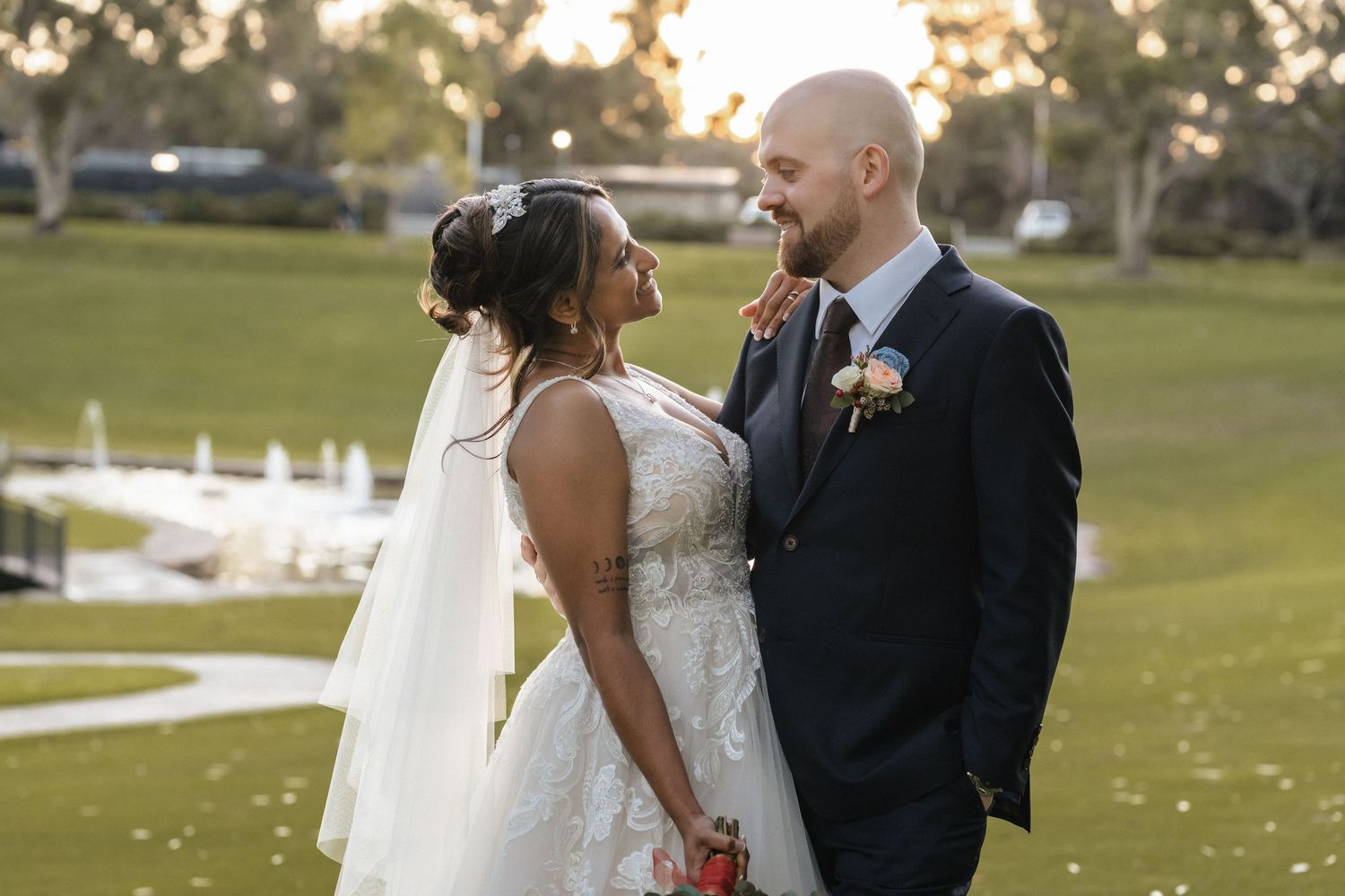 Bride and groom share a romantic golden hour moment on a lush green golf course at their outdoor wedding.