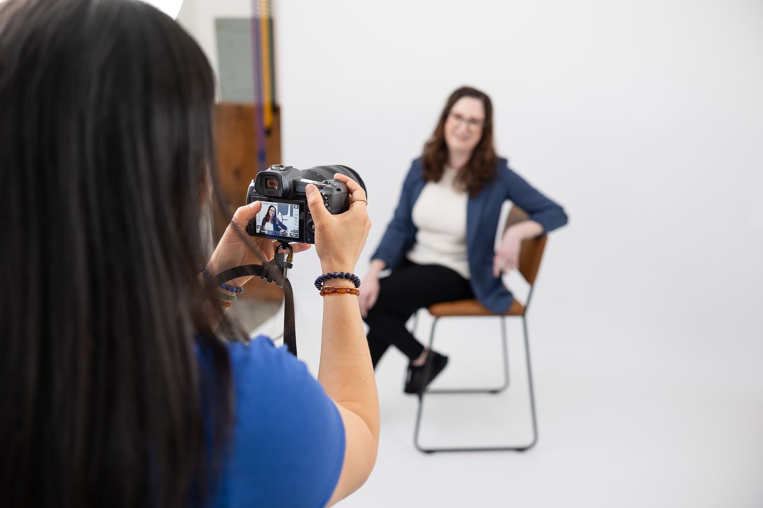 woman photographer taking a headshot of female business owner, focus on back of camera preview of headshot in Auburn, WA studio space