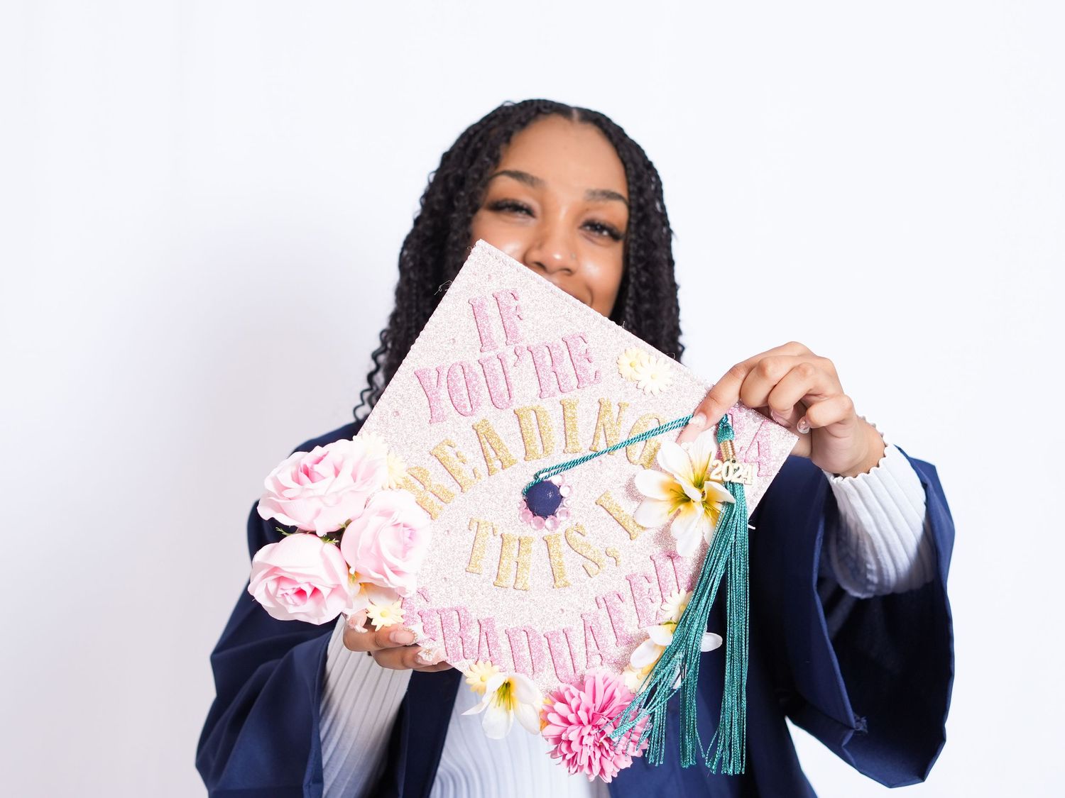 Young woman in navy blue graduation cap and gown posing proudly for a graduation portrait photo.