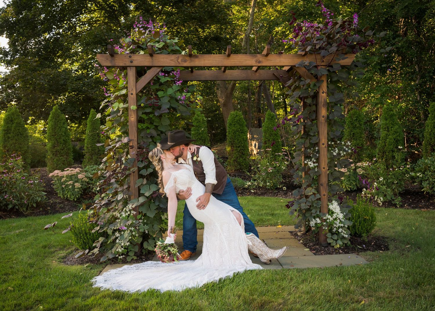 A winter wedding portrait outside a white farmhouse with illuminated windows and a full moon.