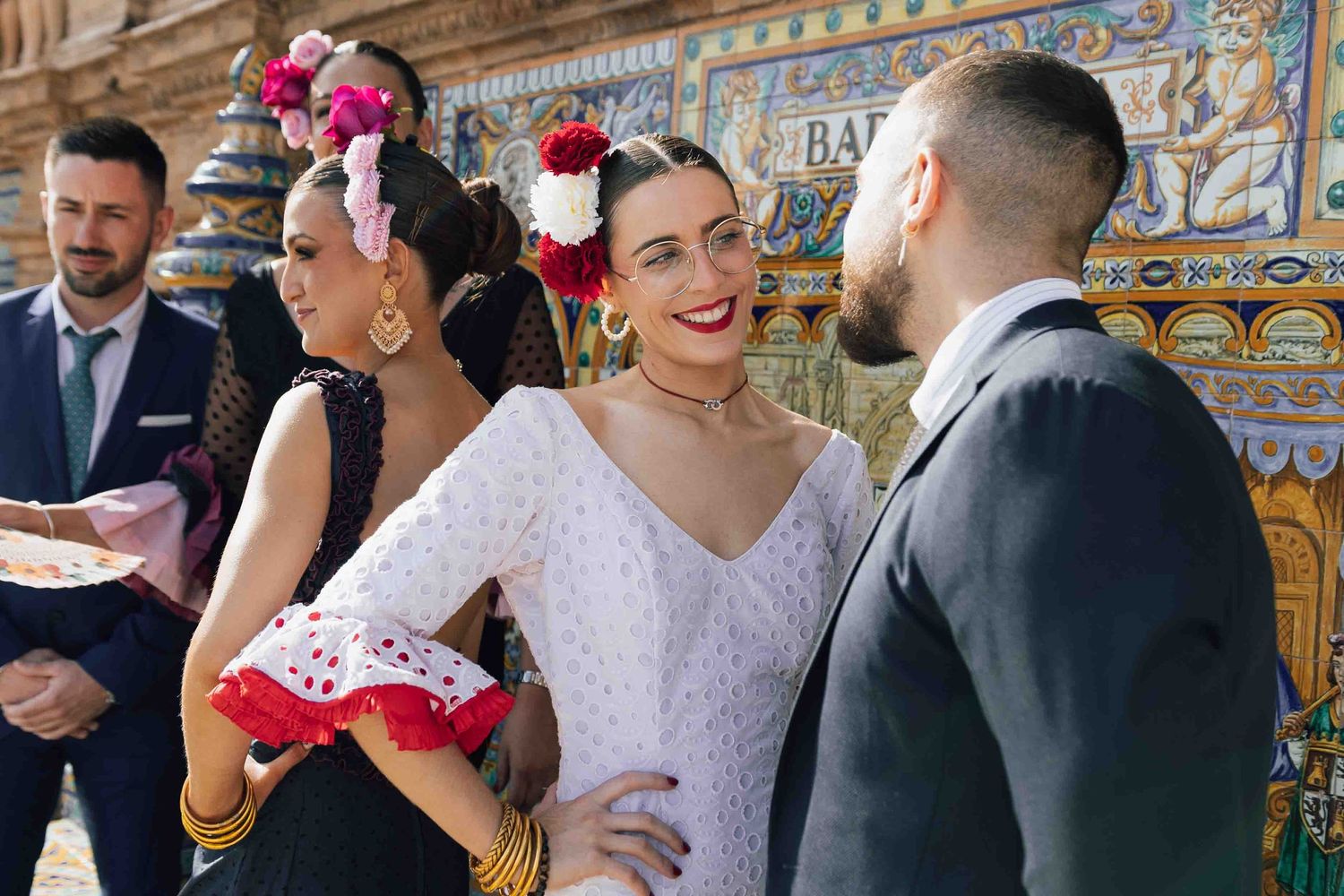 Group in traditional flamenco attire walking at Plaza de España, Seville, Spain.