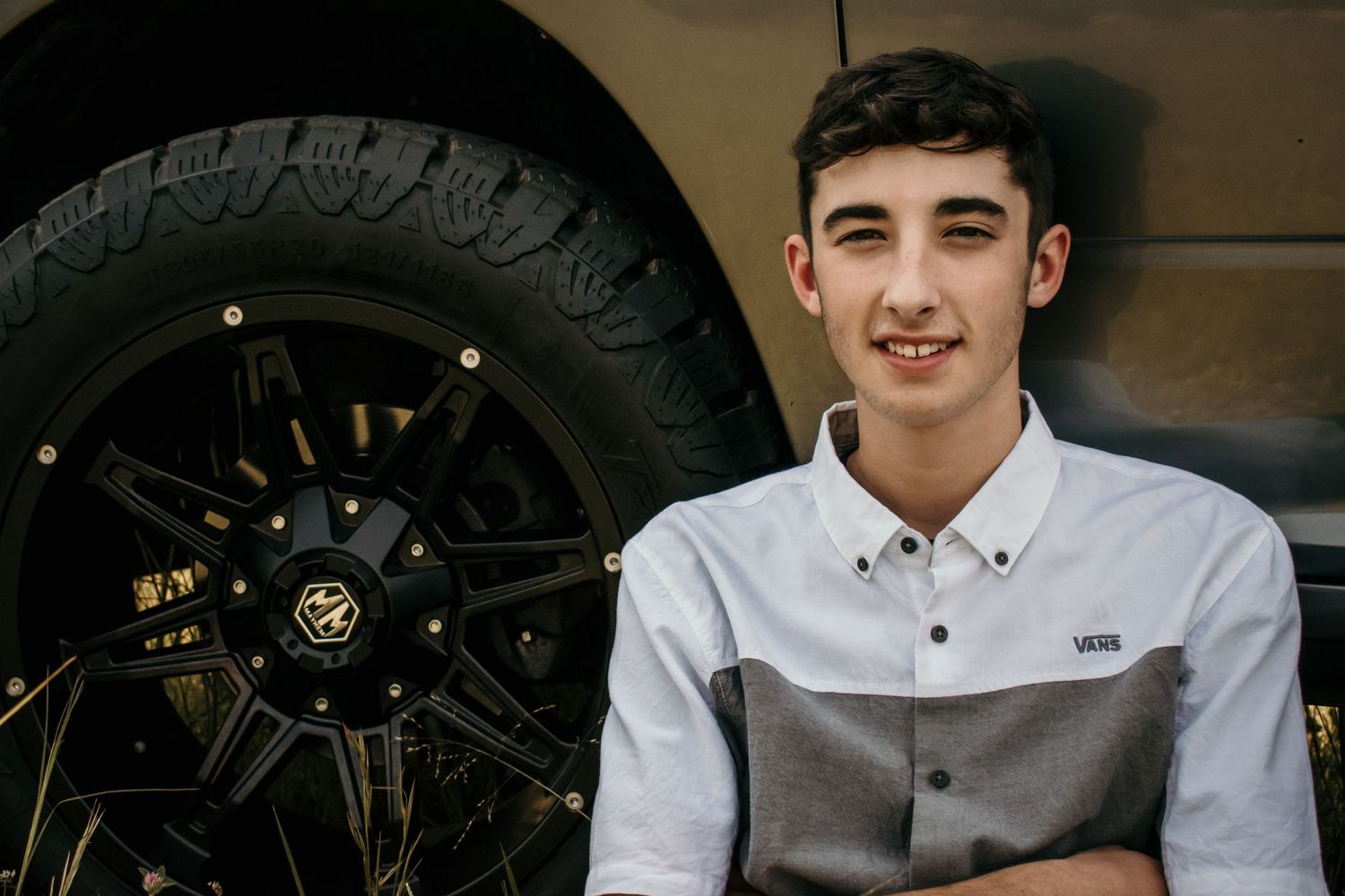 Male graduate posing in front of truck during senior photo session