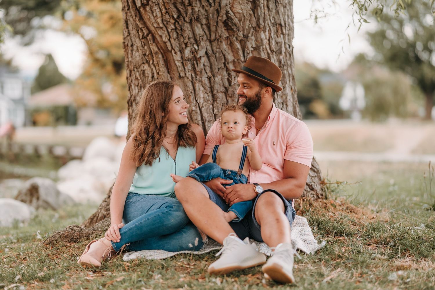 A family relaxing together under a large tree on a sunny autumn day.