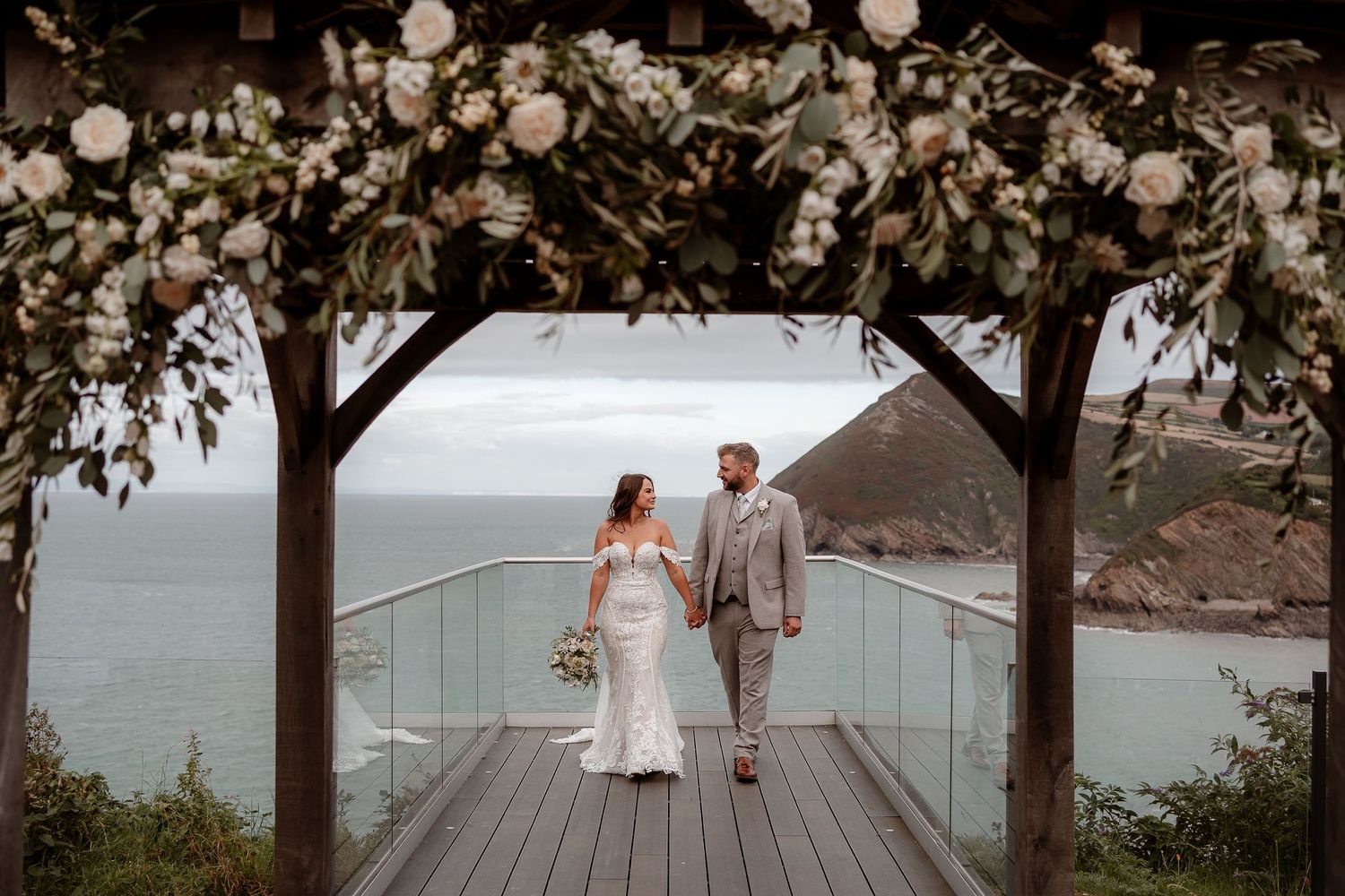 Wedding couple walking along coastal path with ocean views.
