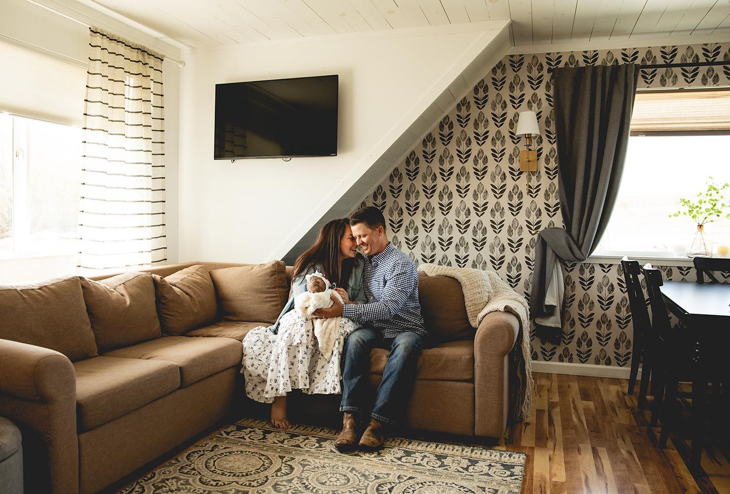newborn photos by brindy ruby photography in client's home with husband and wife snuggling with their newborn baby.
