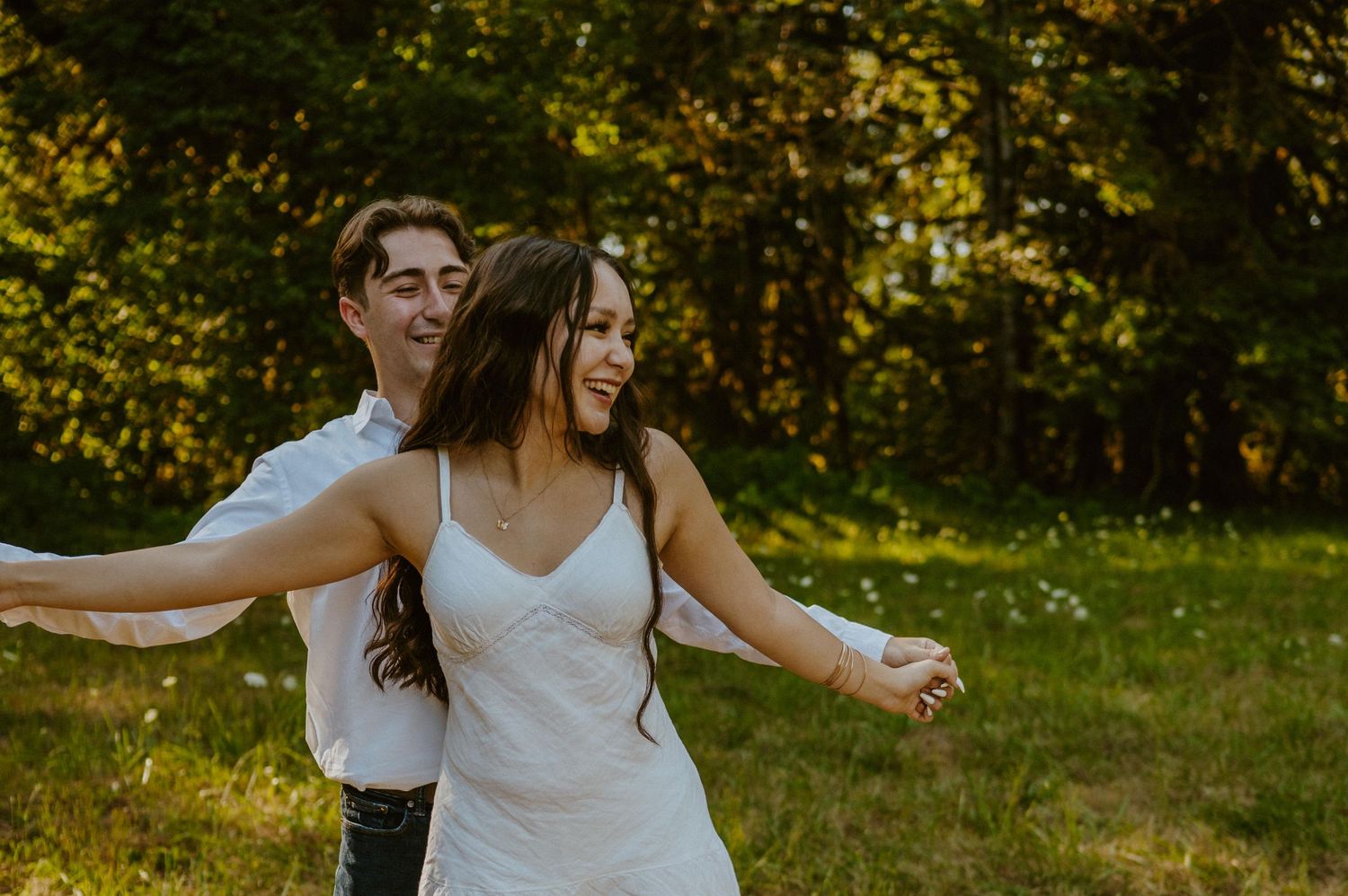 People dancing with arms outstretched in sunlit outdoor setting.