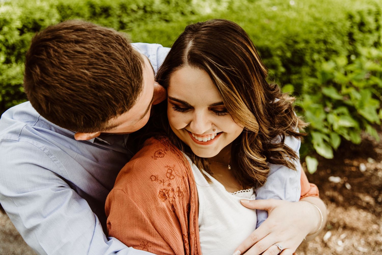 Couple embracing in casual clothing against natural outdoor background.