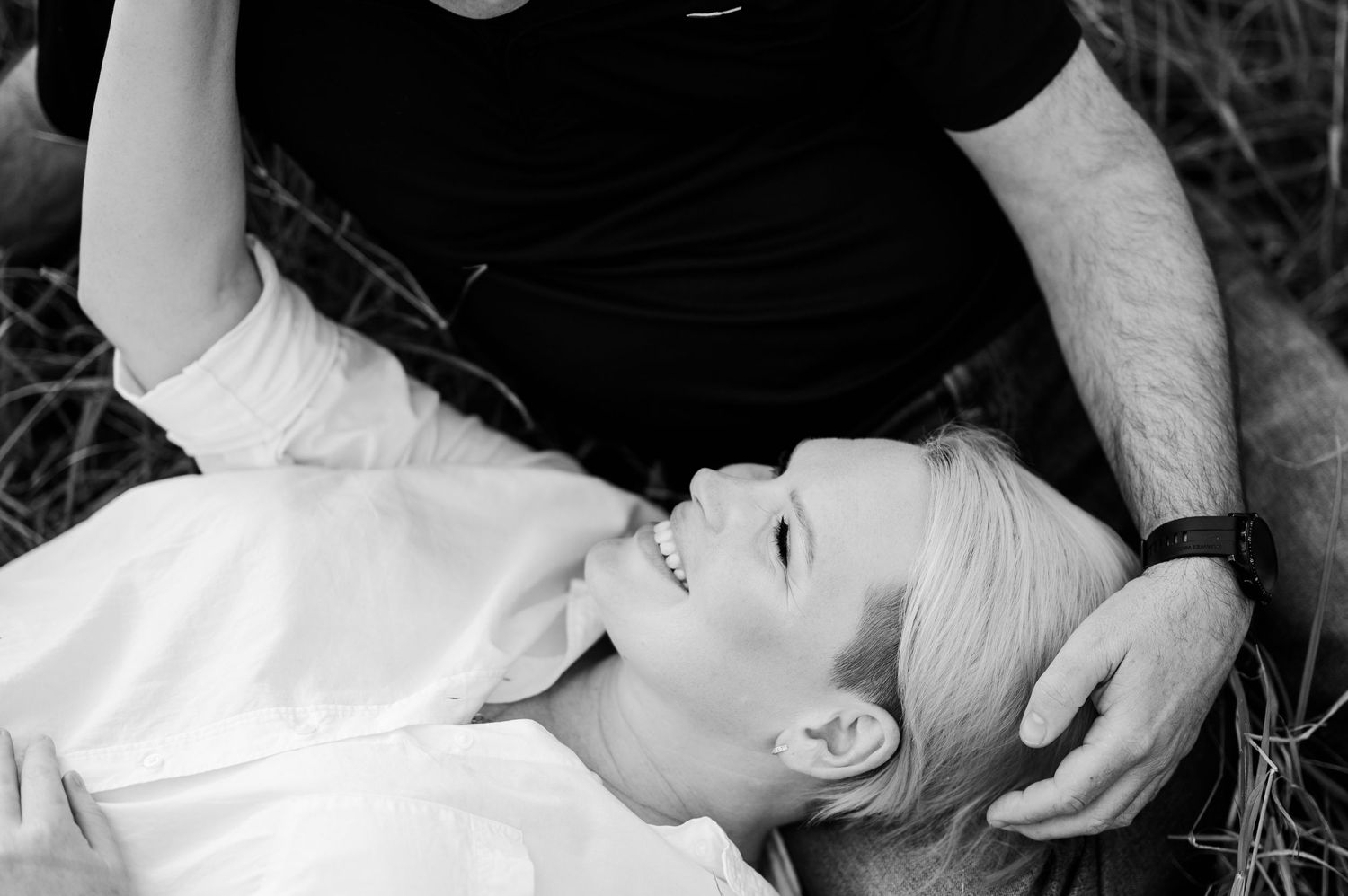 Black and white intimate portrait of a couple laying in grass during outdoor photo session.