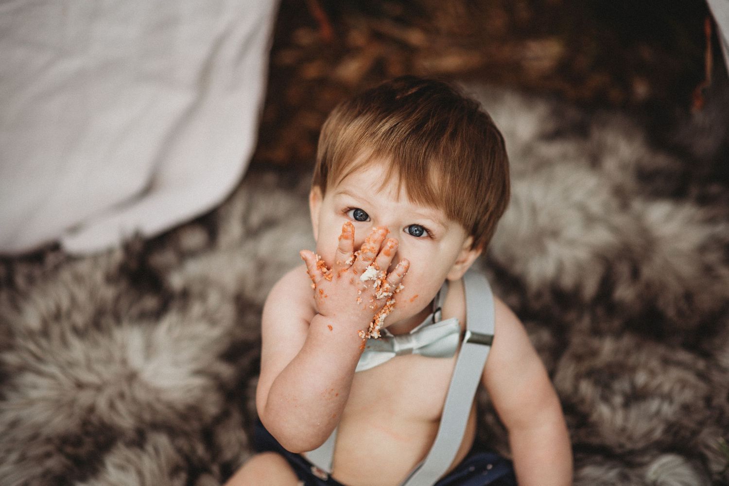 Messy chocolate cake crumbs and frosting on a child's face during a smash cake session.